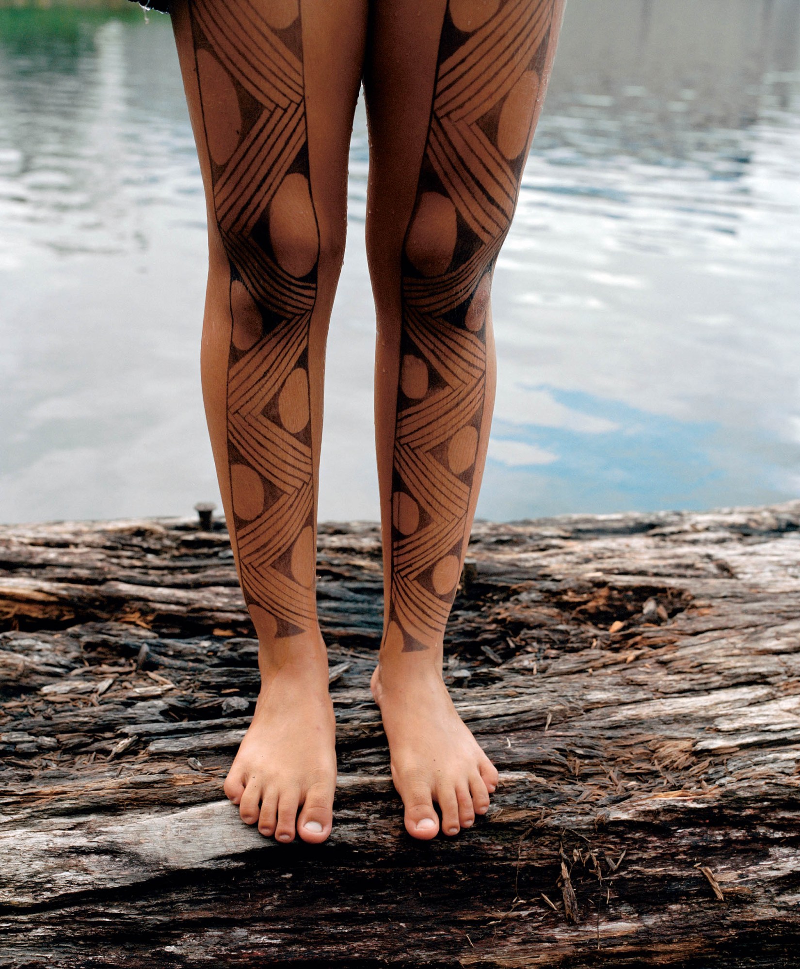 A young person's legs covered in tribal tattoos.