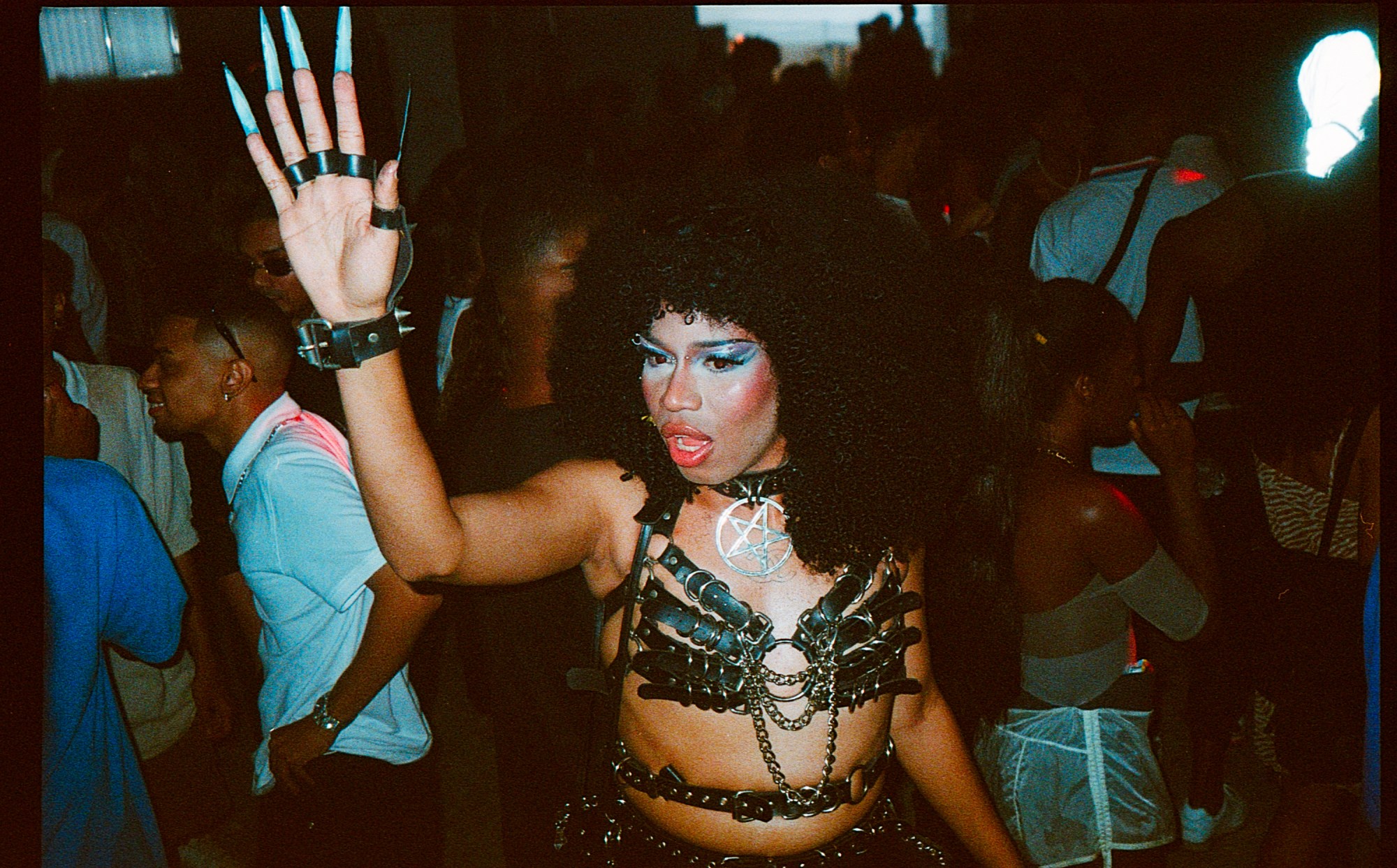 a person with long nails makeup and leather bondage top at a rave in brazil