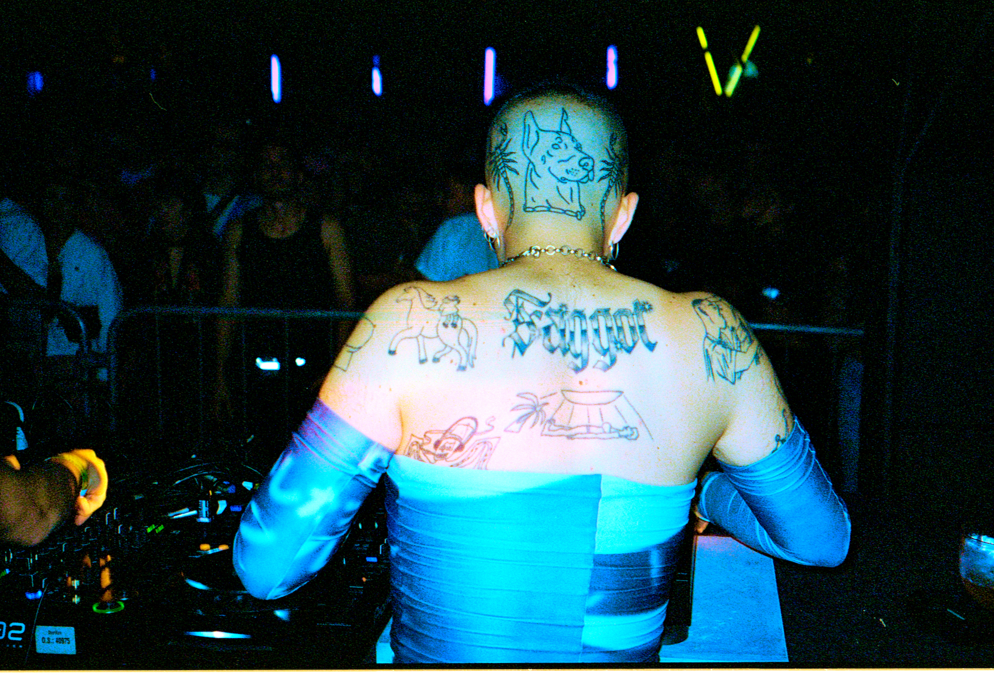 the back of a man with tattoos djing