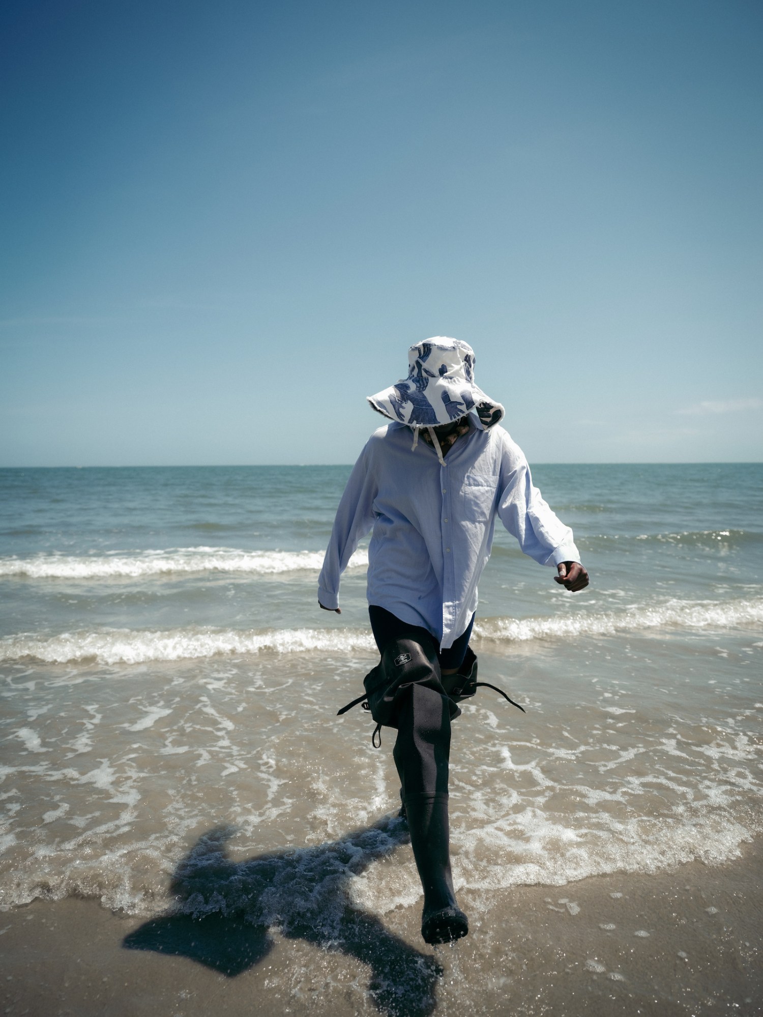 model wearing denim tears clothing on the beach