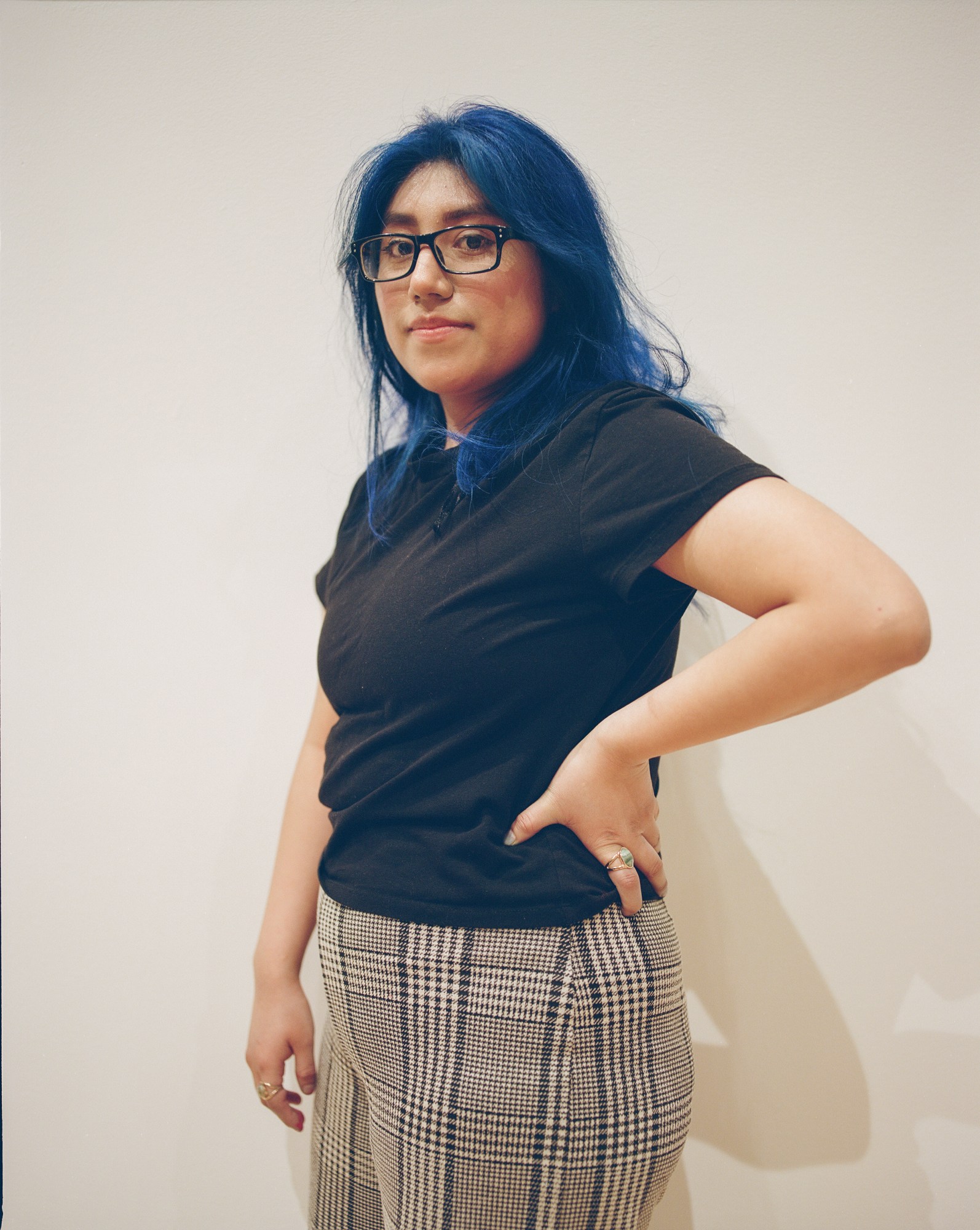 Sandra posing in front of a white wall.