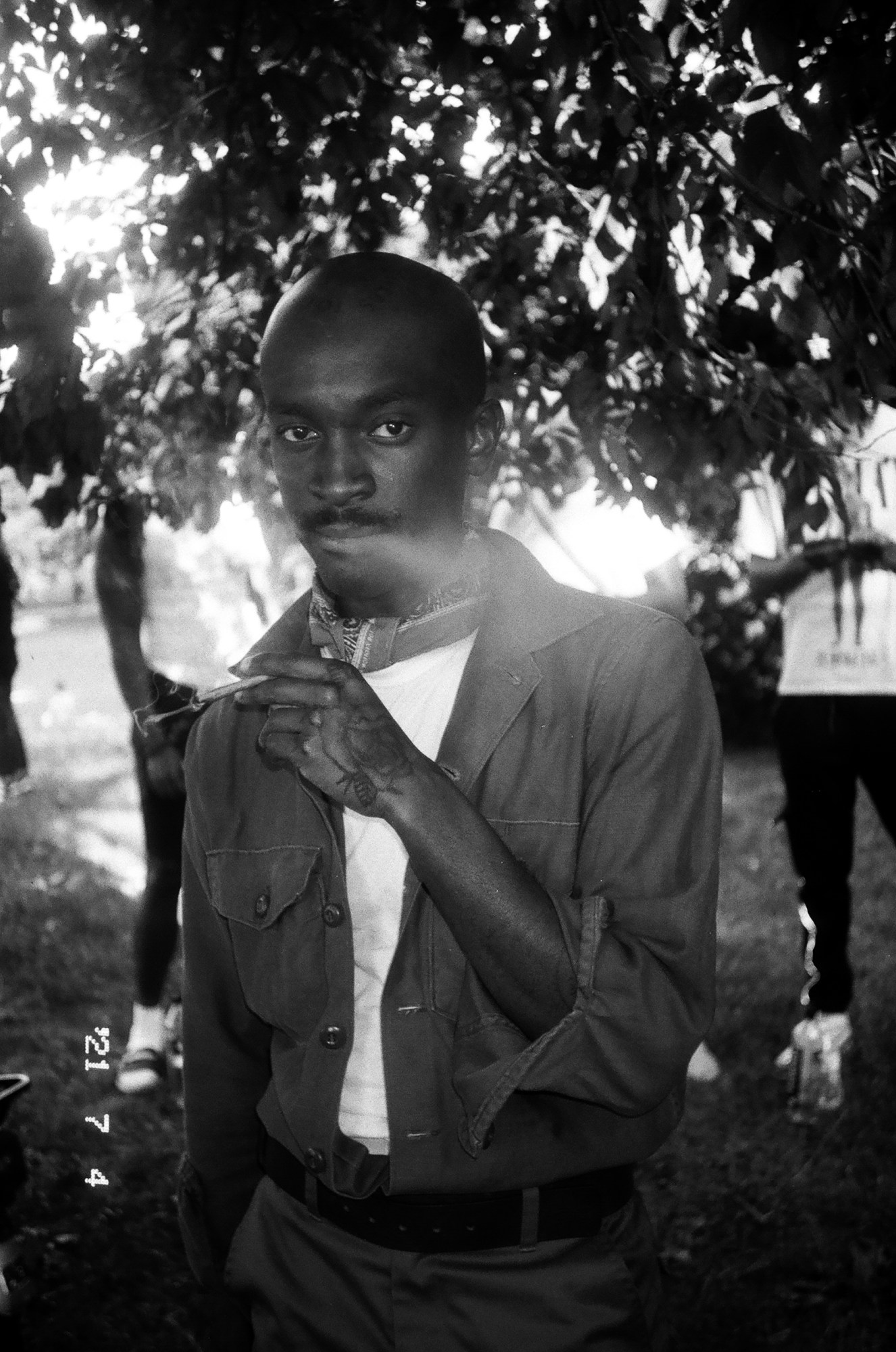 a man wearing a neckerchief smokes and looks into the camera