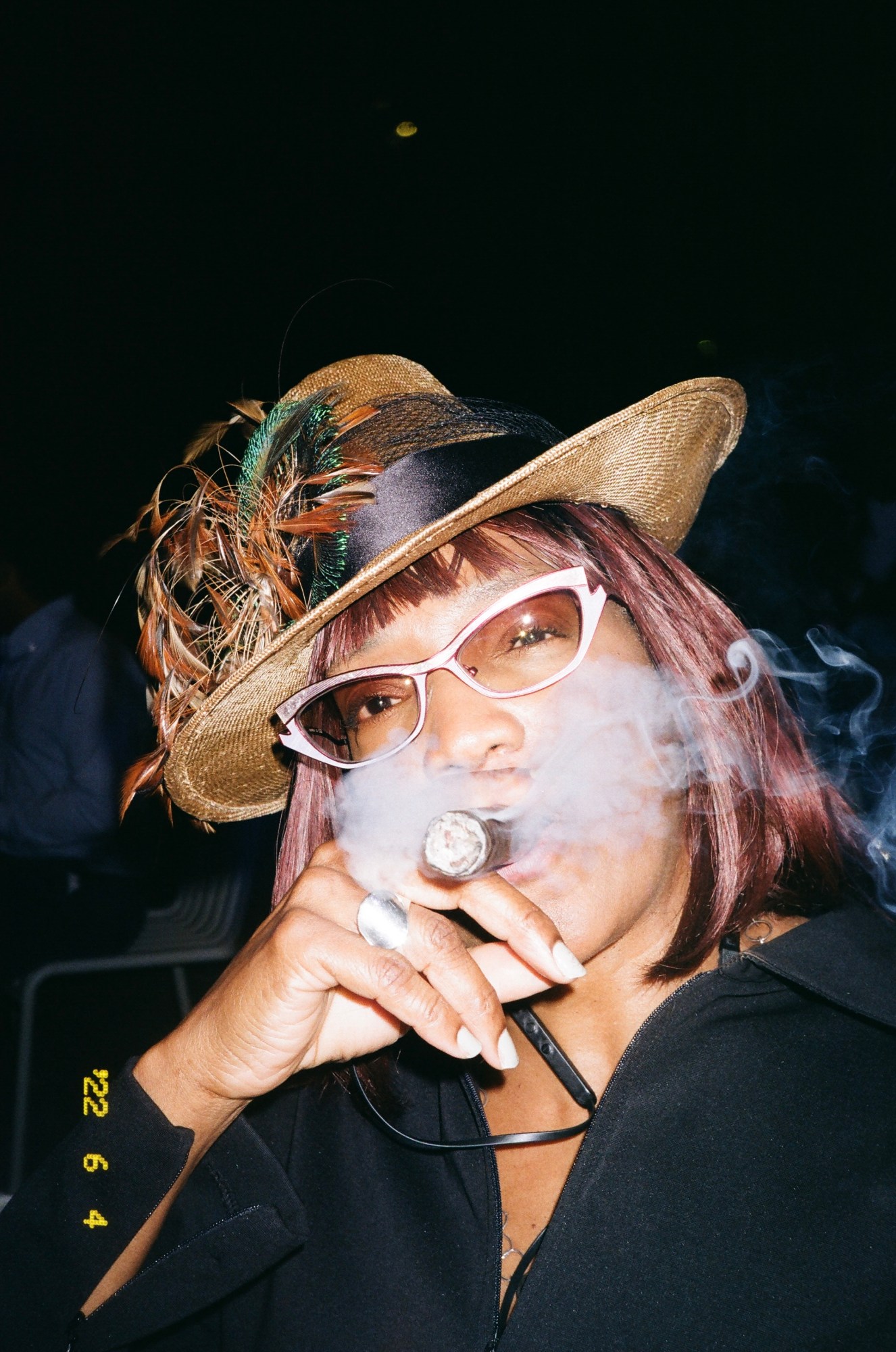 A woman in a straw hat and sunglasses smoking a cigar