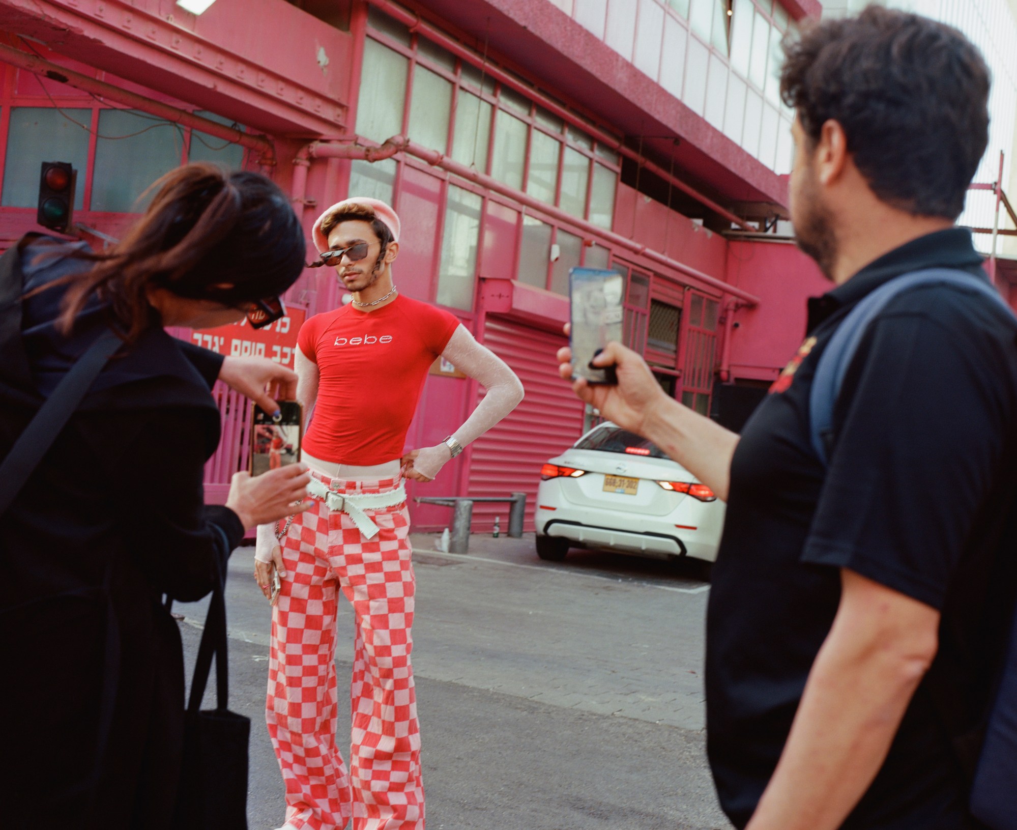 A young Orthodox Jewish man is photographed in a red and pink outfit.