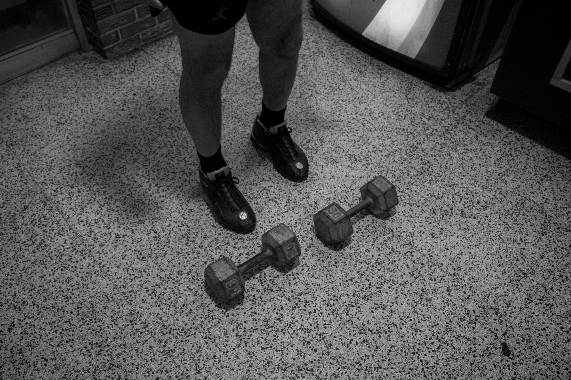 Two dumbells sitting at the feet of a man inside the Lincoln Tunnel Hotel.