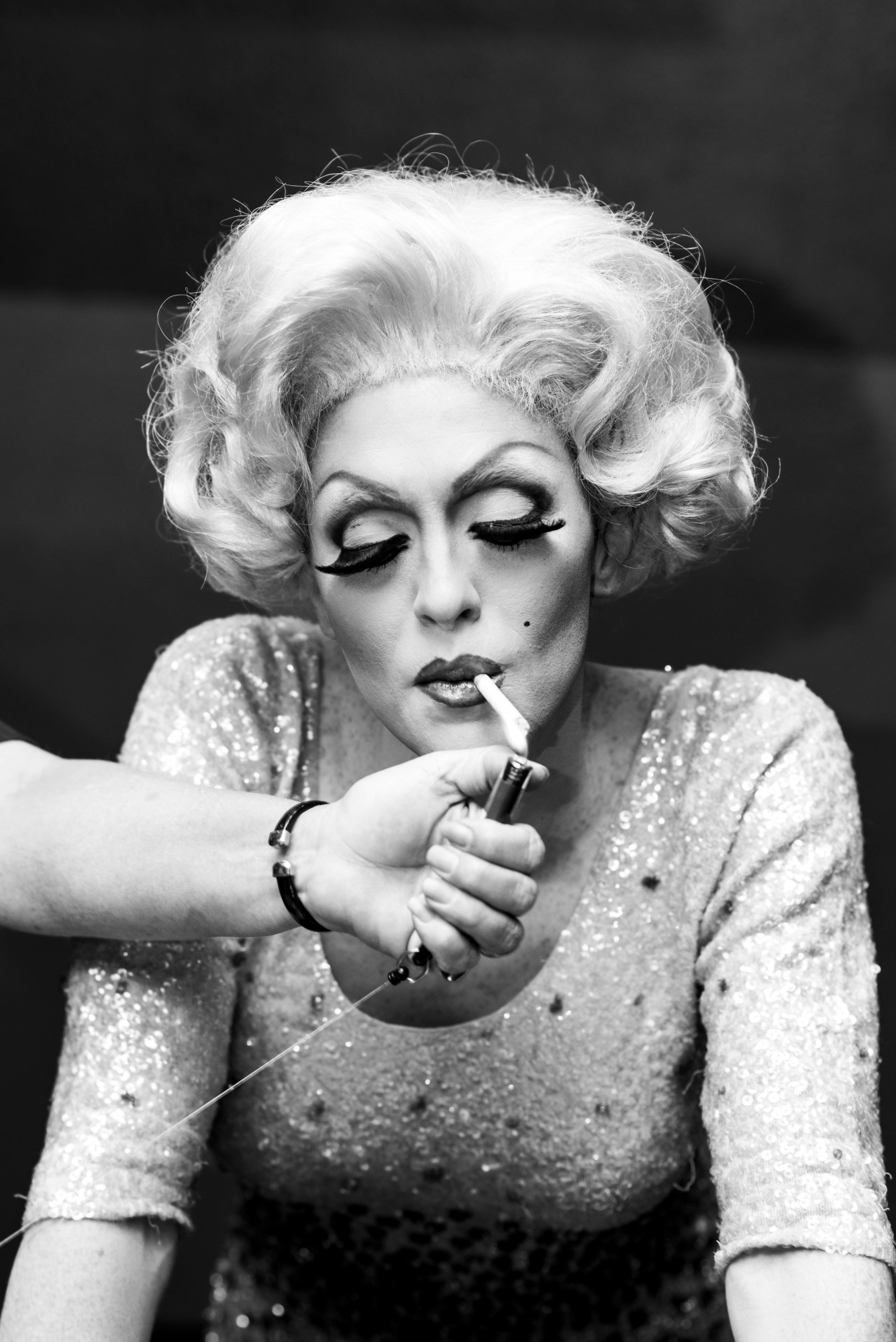 a hand reaching out to light a cigarette for a drag queen