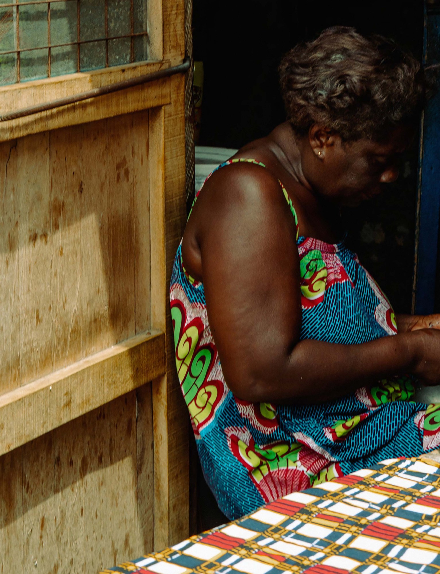 A woman seated at the entrance of her home, Prof. Atta Mills, Accra