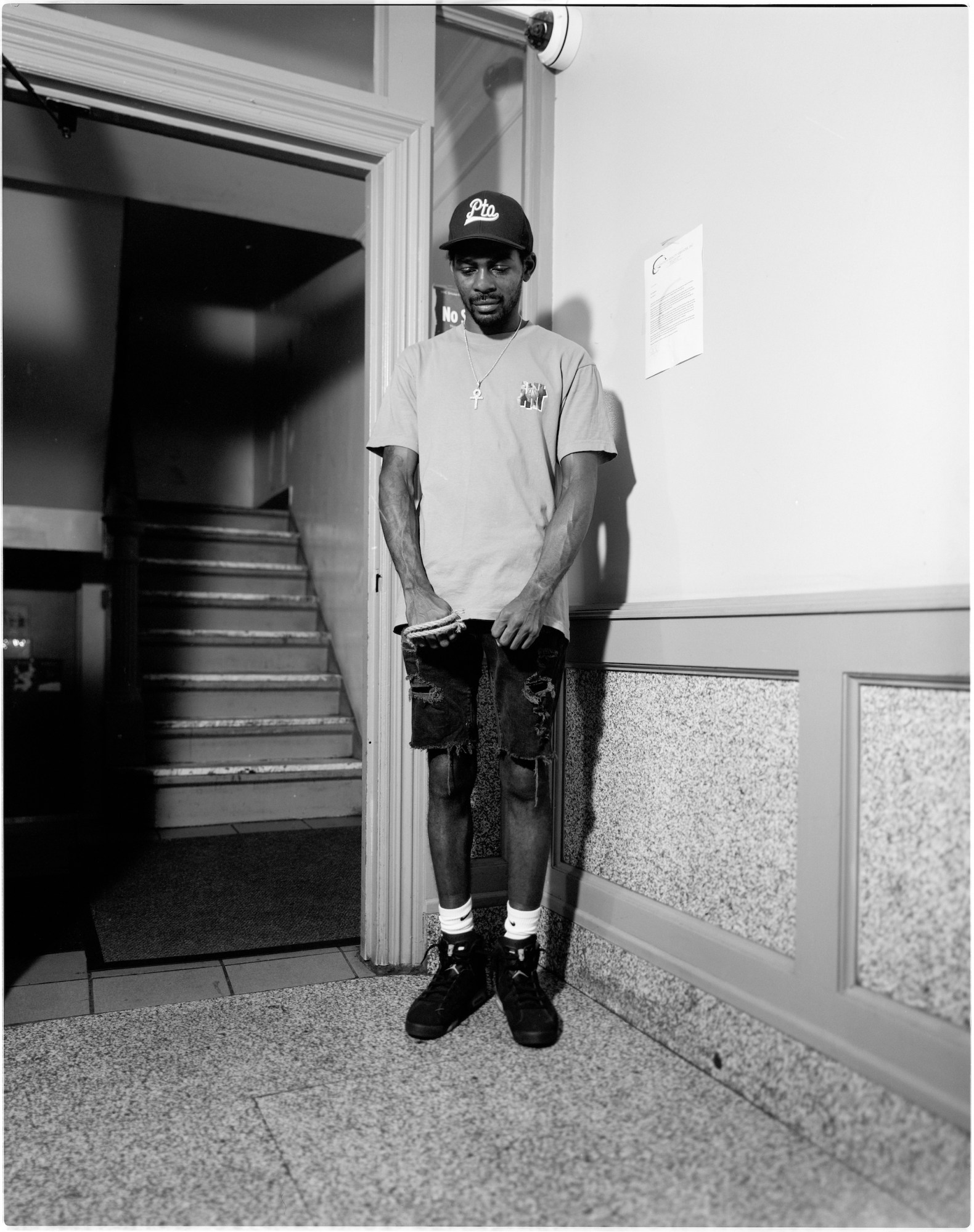 A man wearing a hat standing in a hallfway.