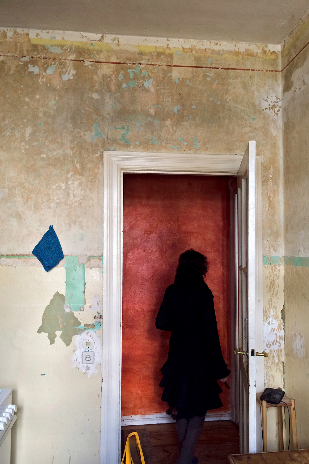 a woman wearing black walking out of a door in an old house