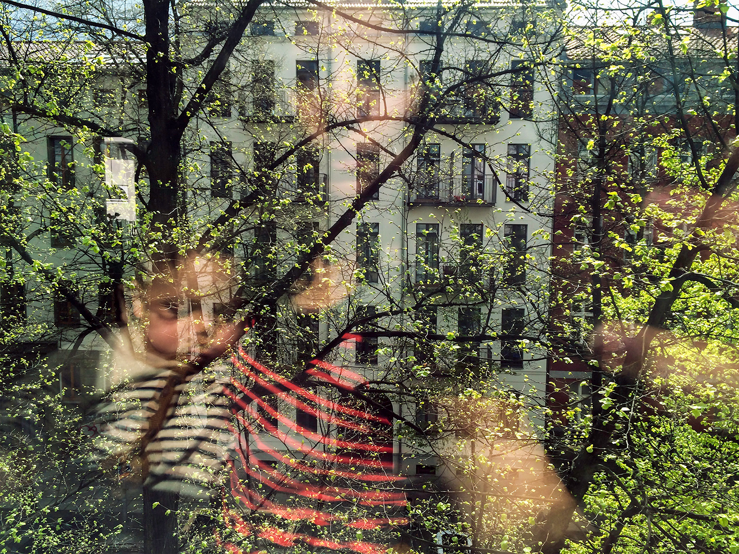 a woman and child's reflection in a window looking out at a white house and green trees