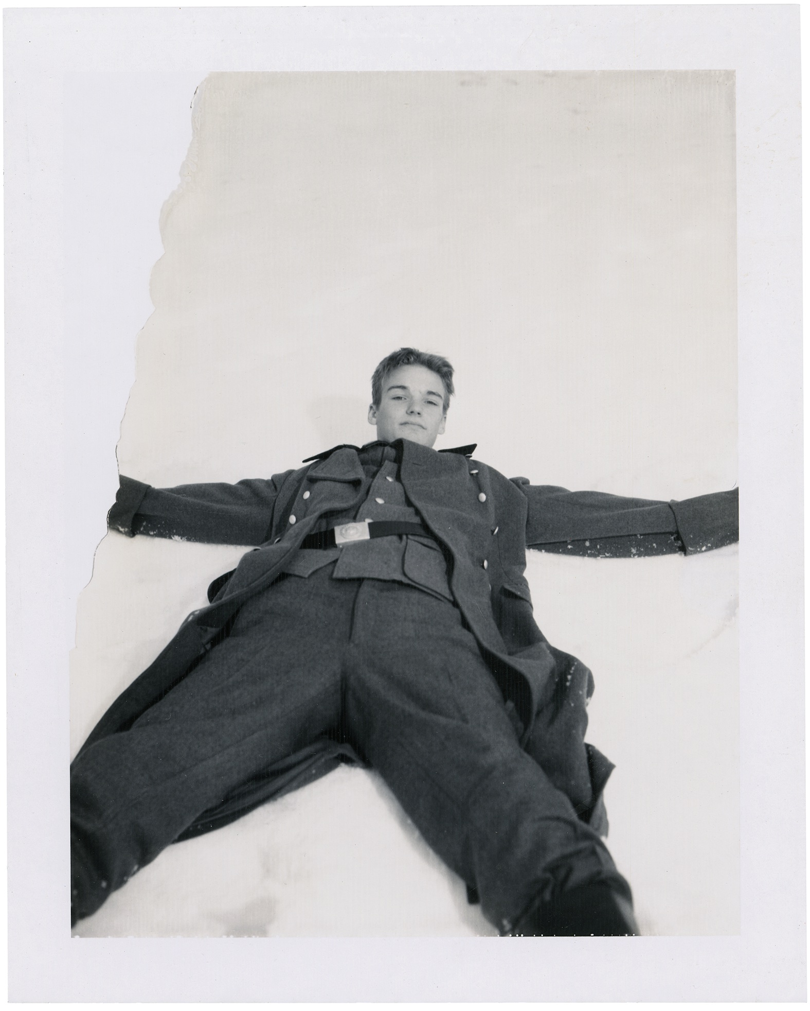 Polaroid of a boy in German military wear lying in the snow