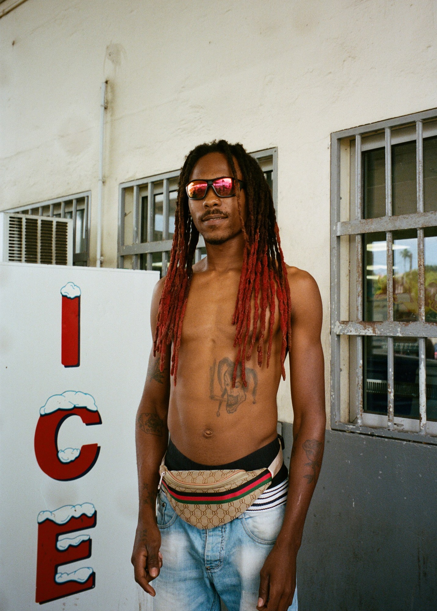 a man with red dredlocks posing in front of an ice box