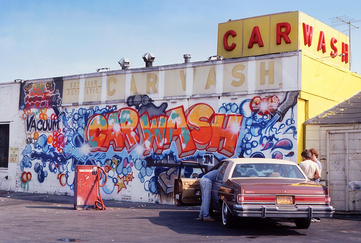 a carwash covered in graffiti advertising the carwash, with cartoon bubbles, etc.