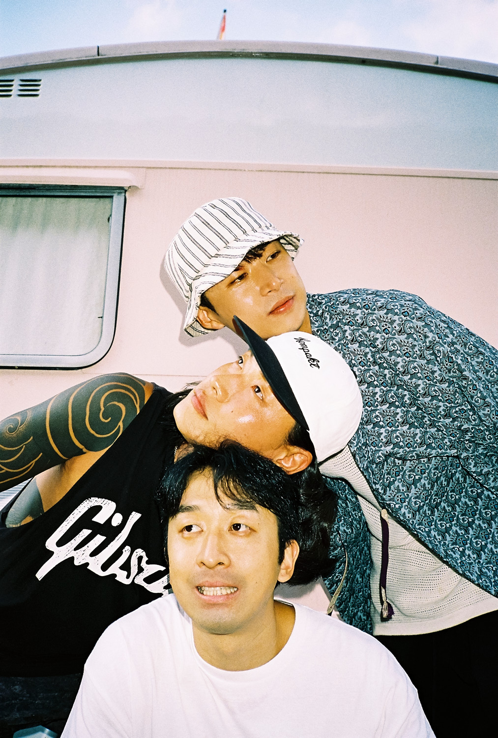 three members of the band cadejo pile their heads on top of one another