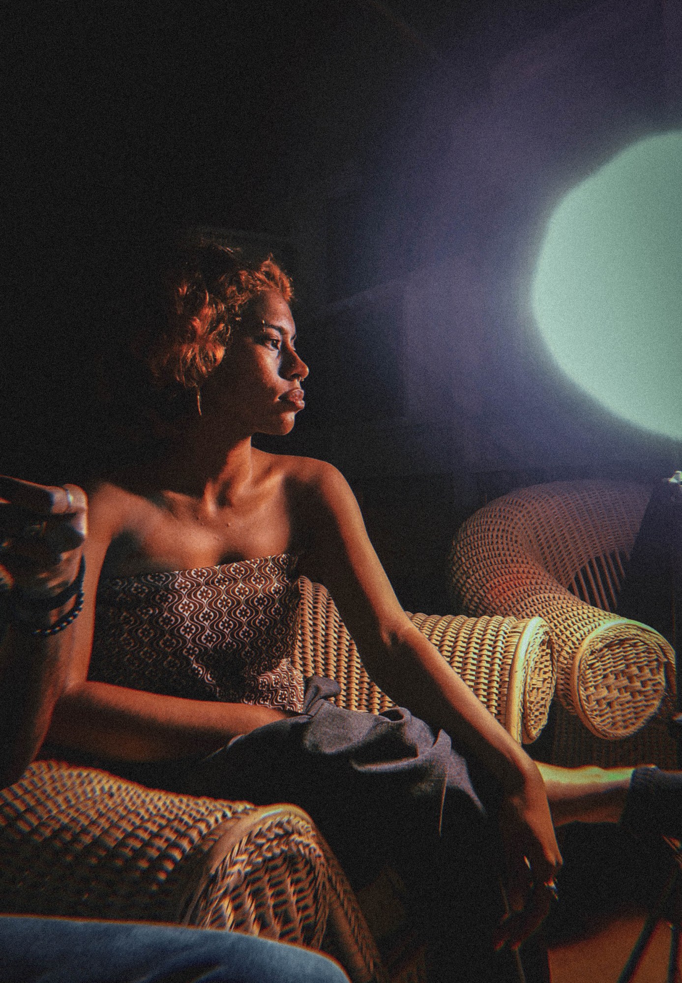 a young woman sits in a wicker chair