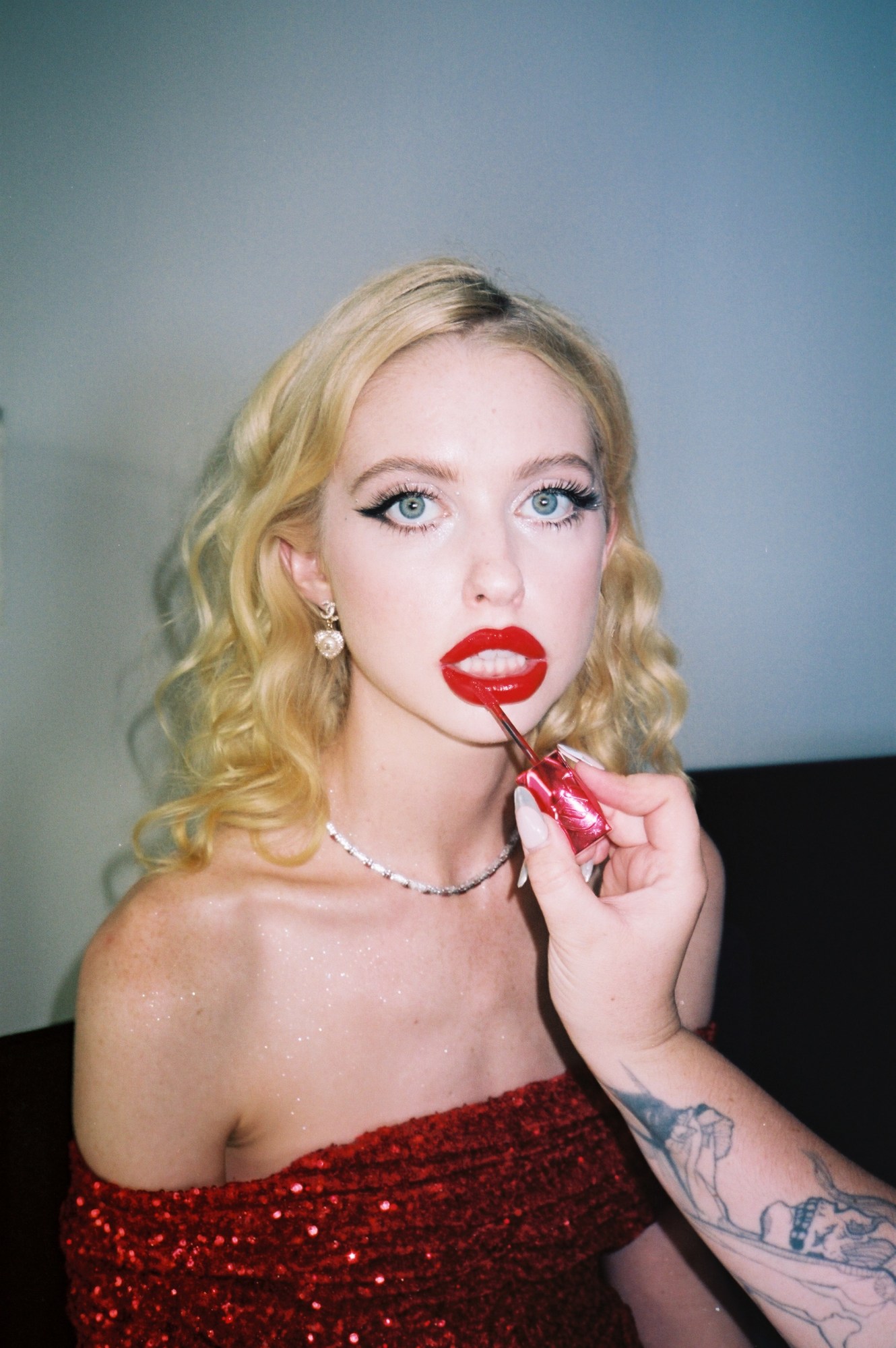 chloe cherry having her glossy red lipstick applied, looking down the camera