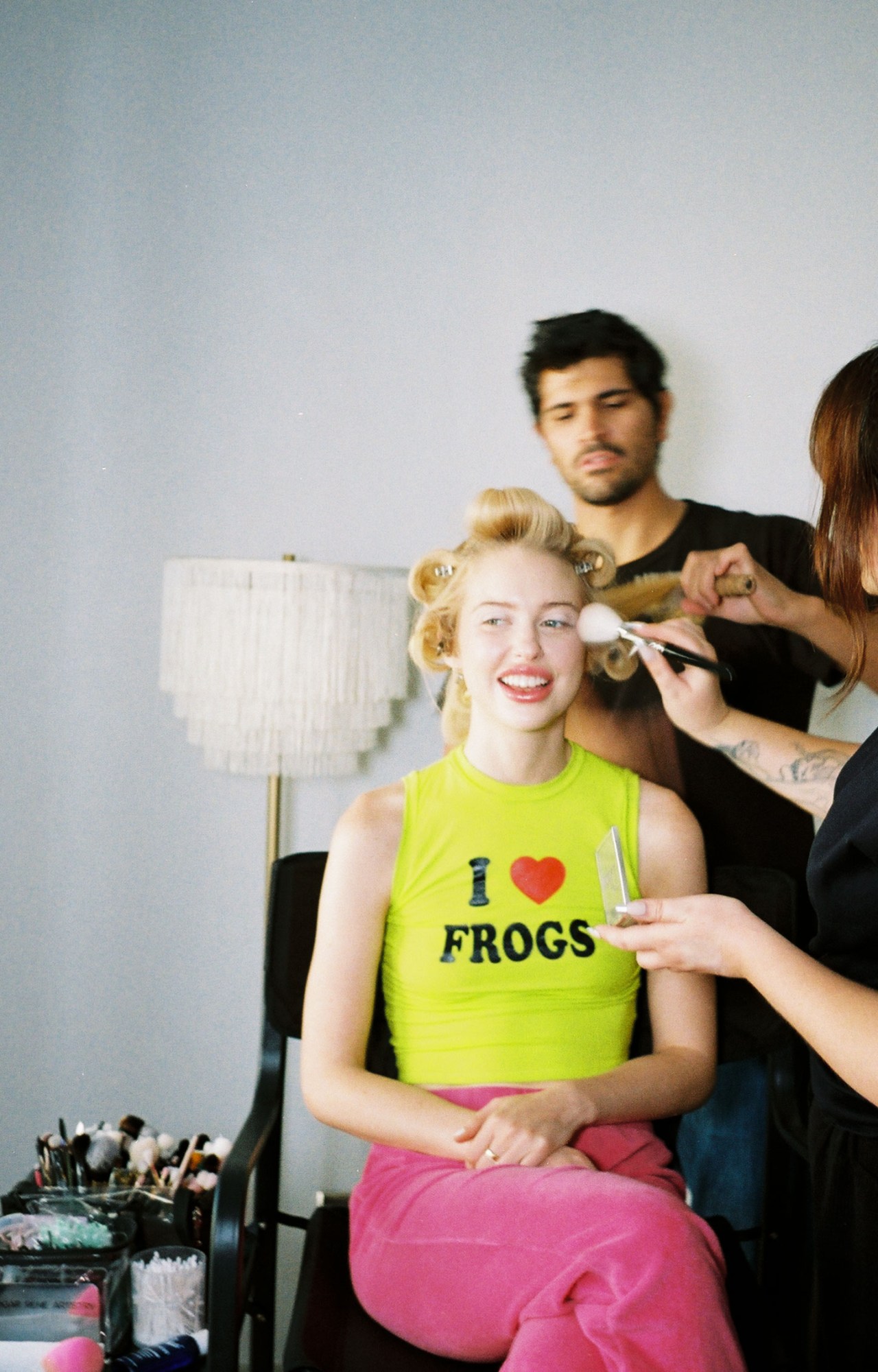 chloe cherry, in pink sweatpants and a yellow I heart frogs tank, has her hair and makeup done