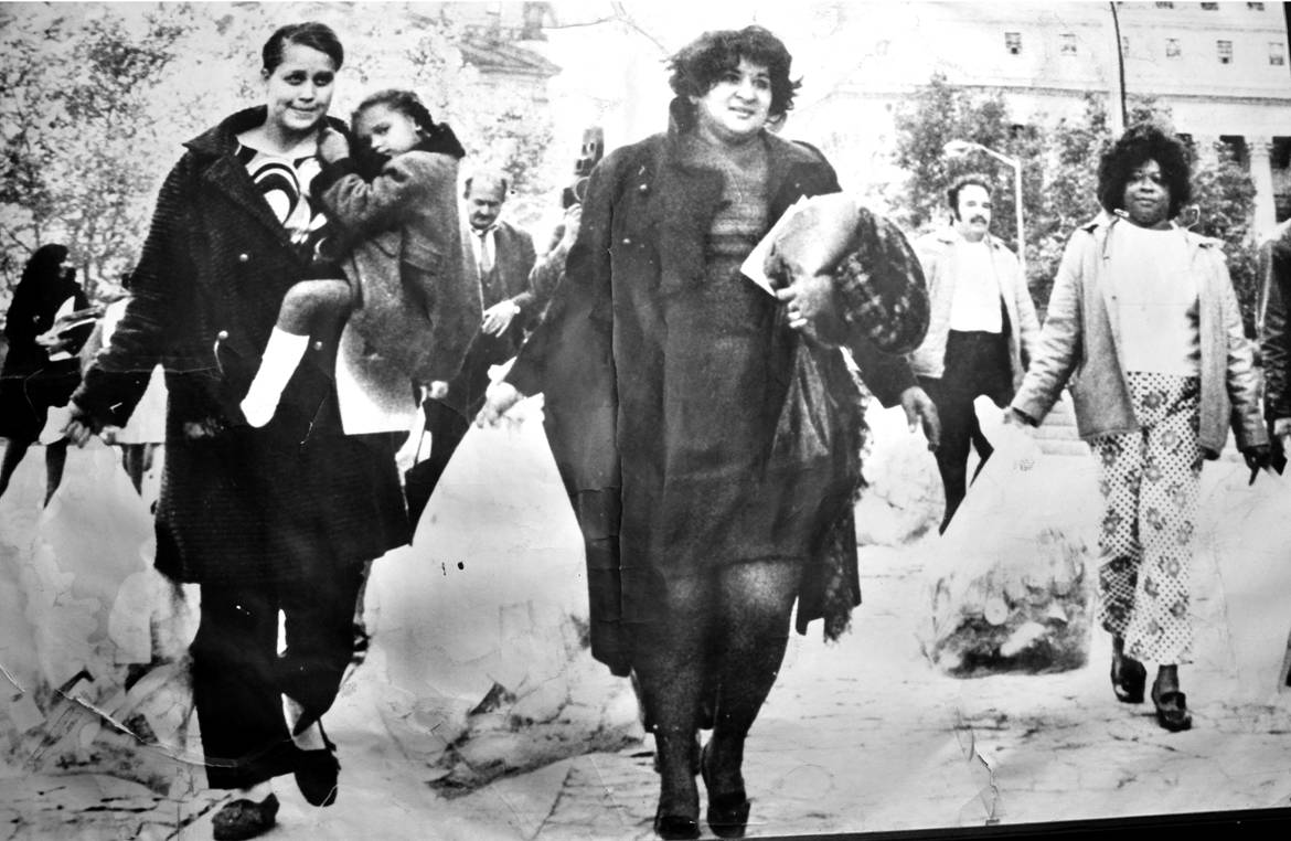 black-and-white photo of Dr. Evelina López Antonetty walking with others all holding rubbish bags