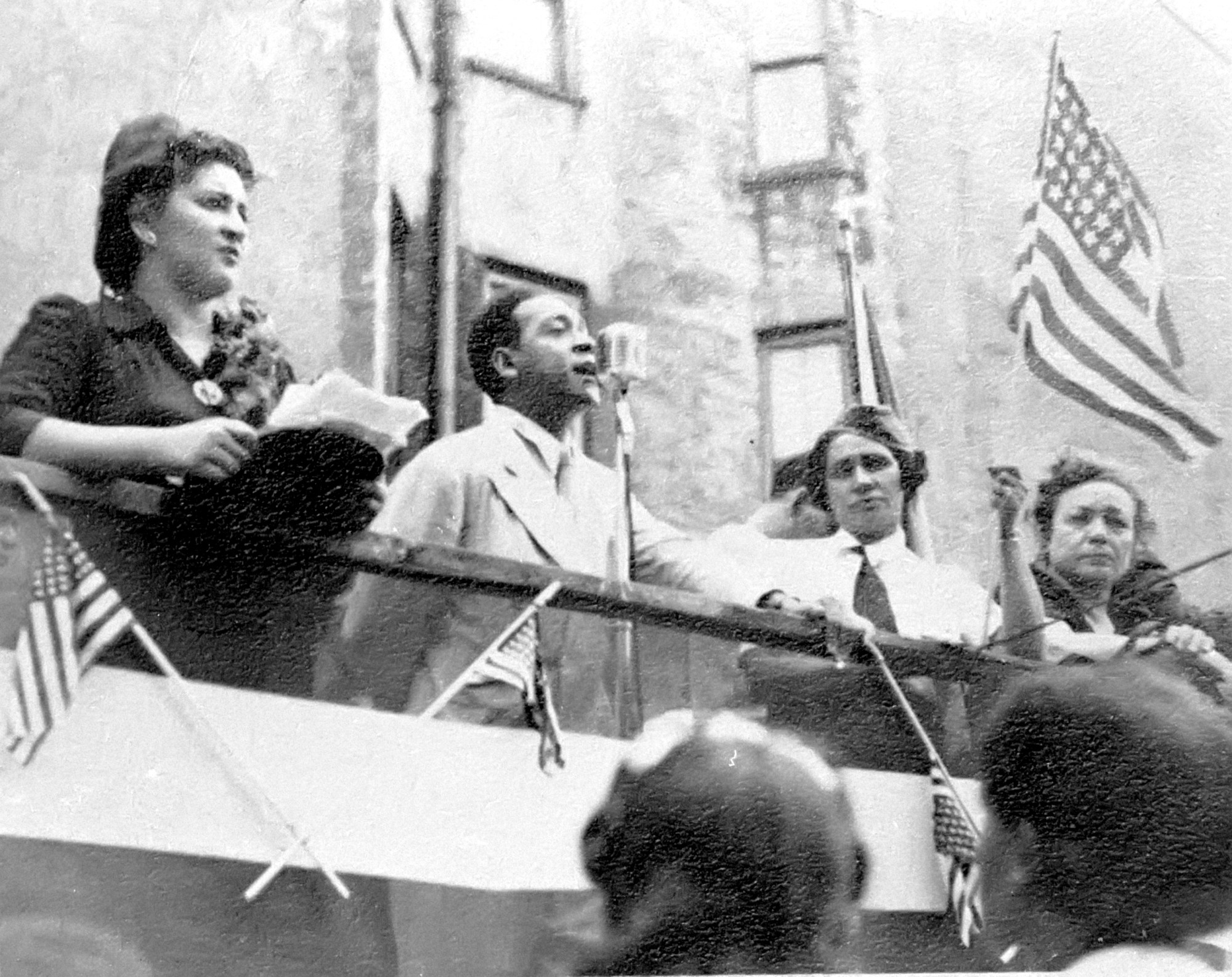 black-and-white photo of Dr. Evelina López Antonetty speaking at a protest on stage with titi and jesus colon