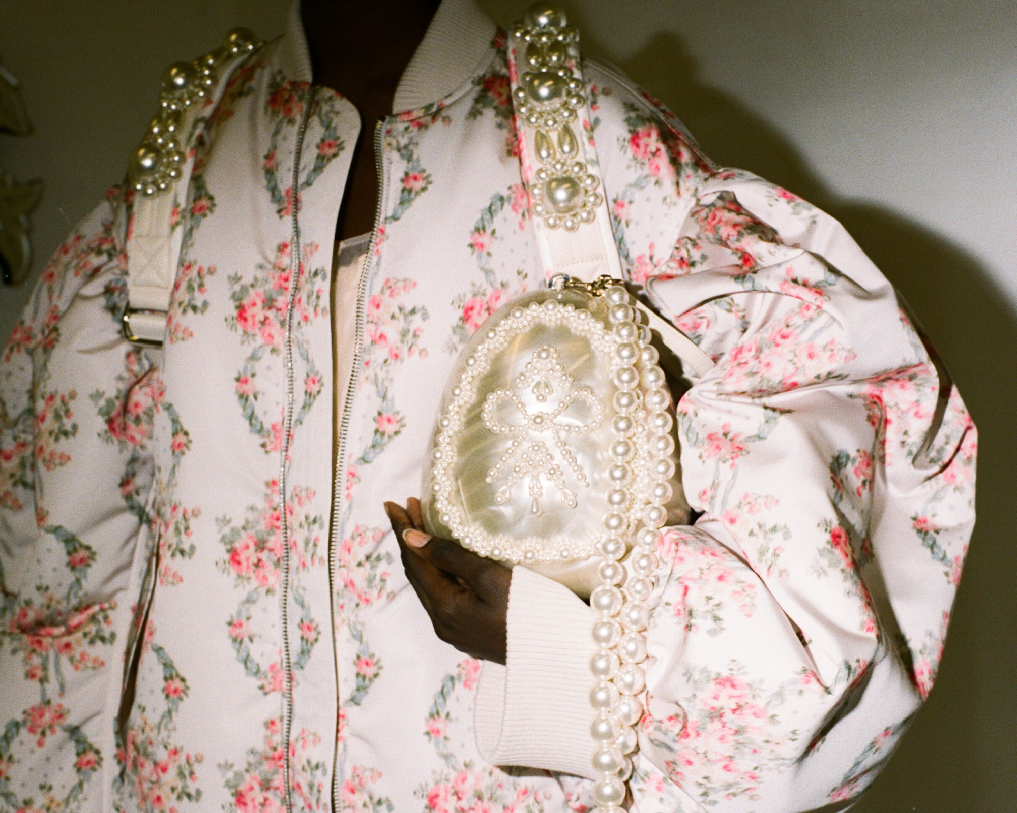 Model behind the scenes at Simone Rocha SS23 in a pink floral jacket and pearl bag