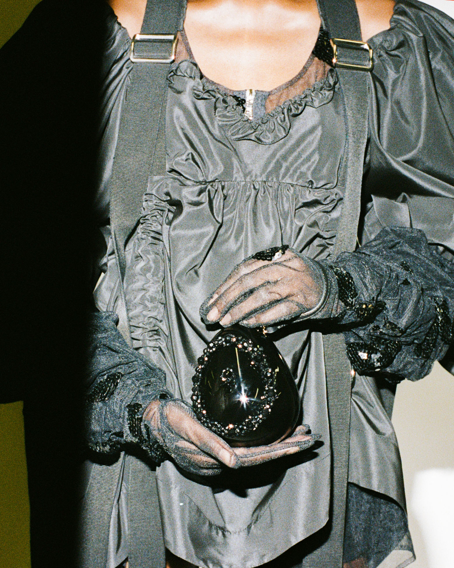 Model behind the scenes at Simone Rocha SS23 in a black dress and a black bag