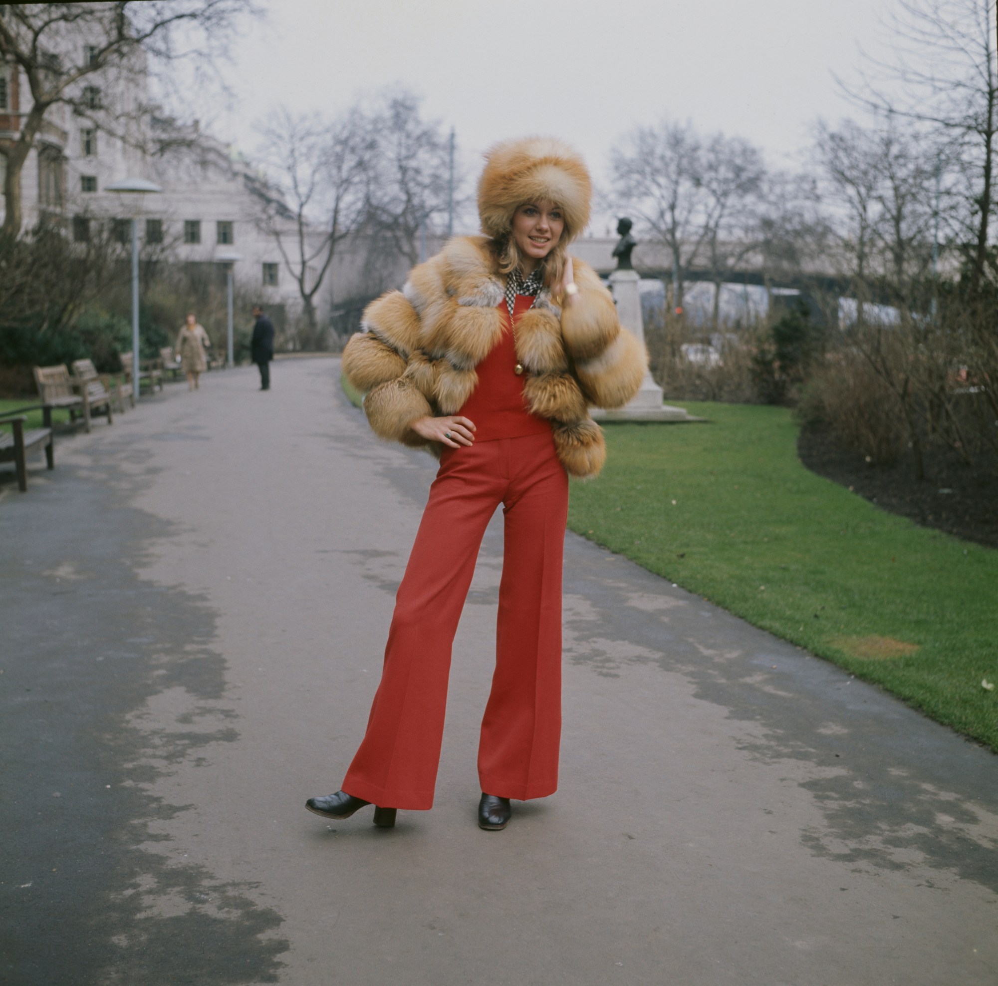 Olivia on a path outside wearing red flares and a fur jacket