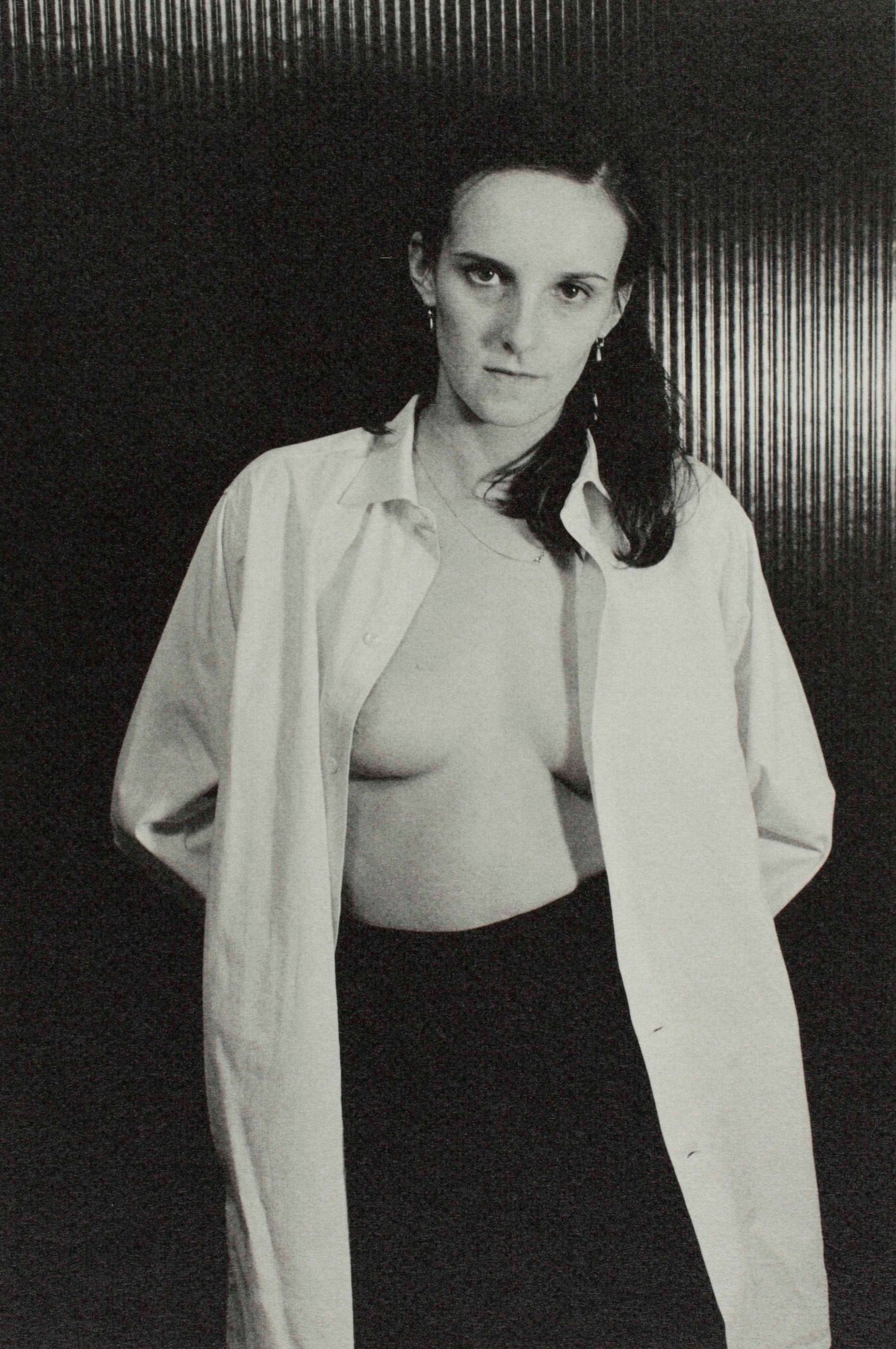 black-and-white image of a woman in a white shirt opened with bare chest underneath