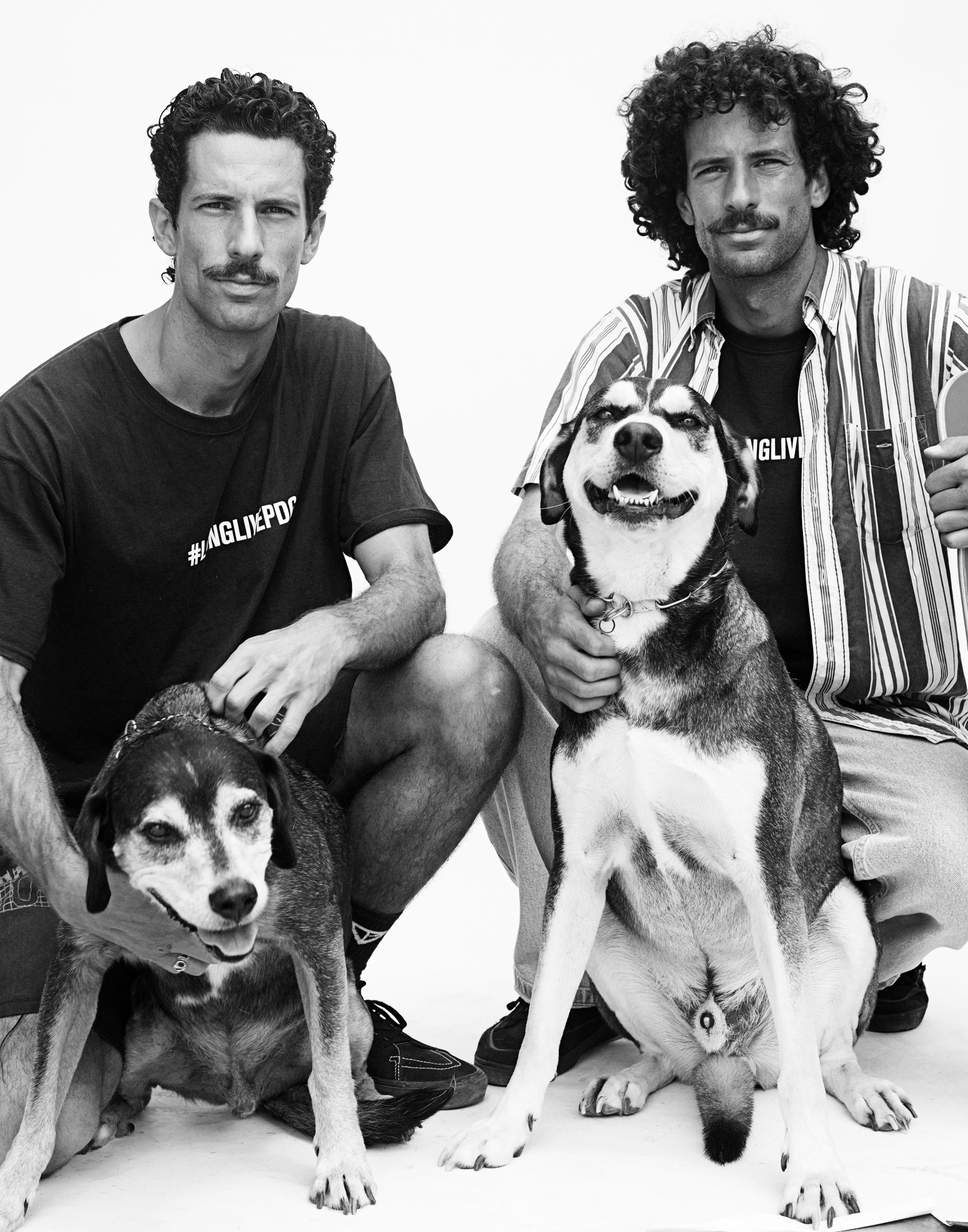 twin brothers bernard and laurence pose down in a squat with their dogs