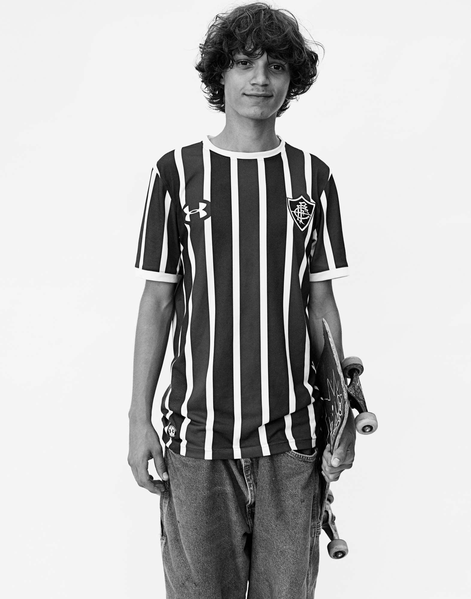 a young model in baggy clothes stands holding a skateboard