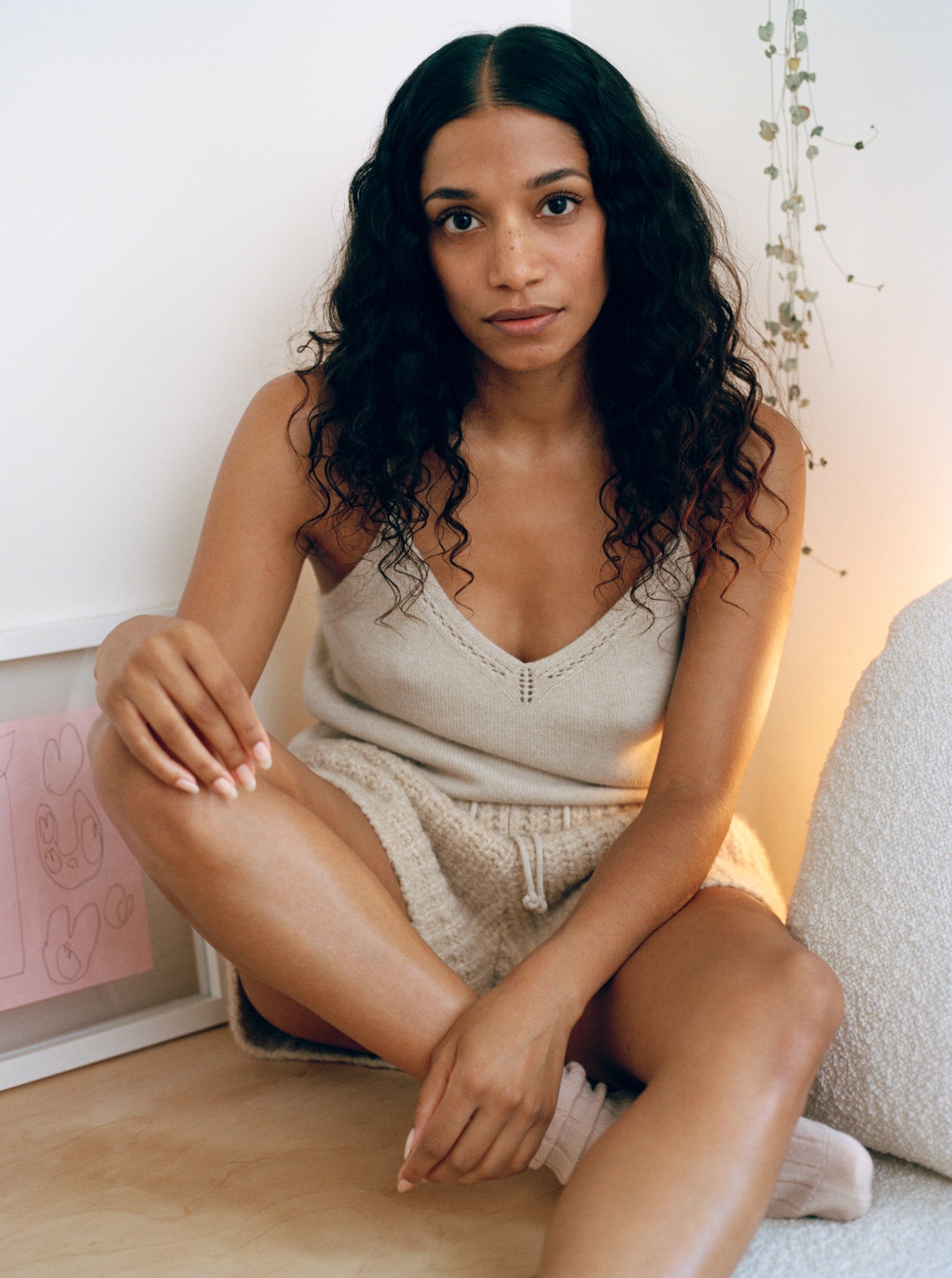 Woman sits cross legged against a white wall wearing Loro Piana cocooning collection