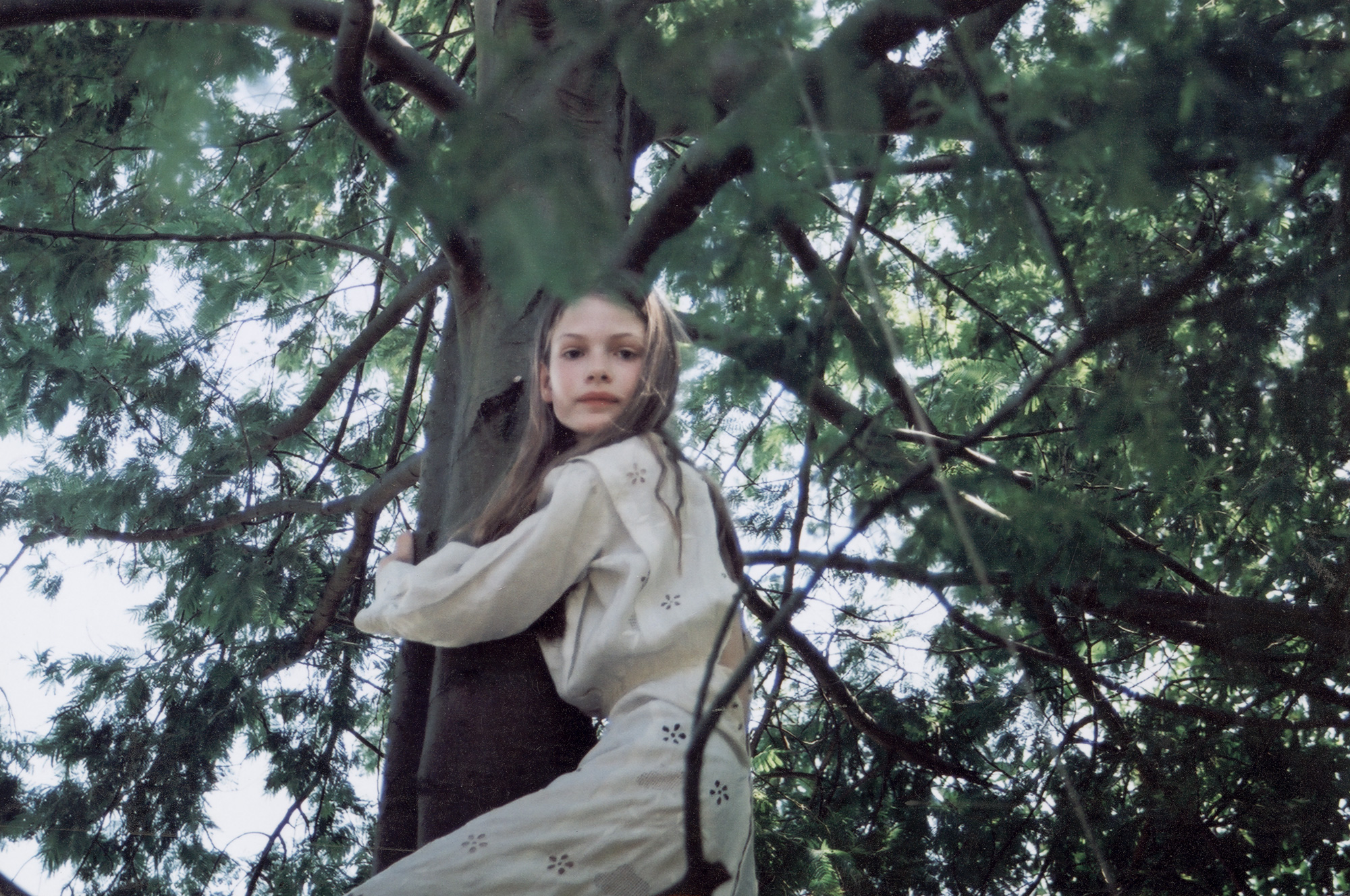 sylvia shot by angela hill in white dress climbing a tree