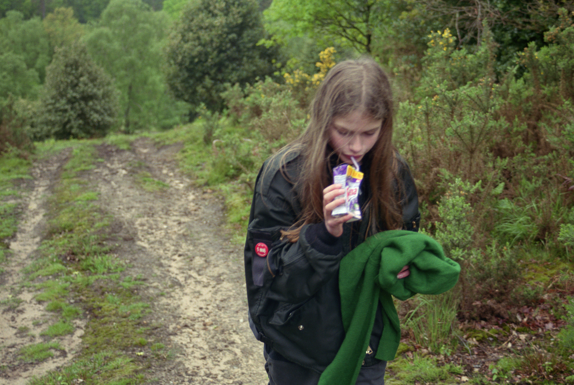 sylvia by angela hill walking through a path in the woods wearing a black bomber jacket