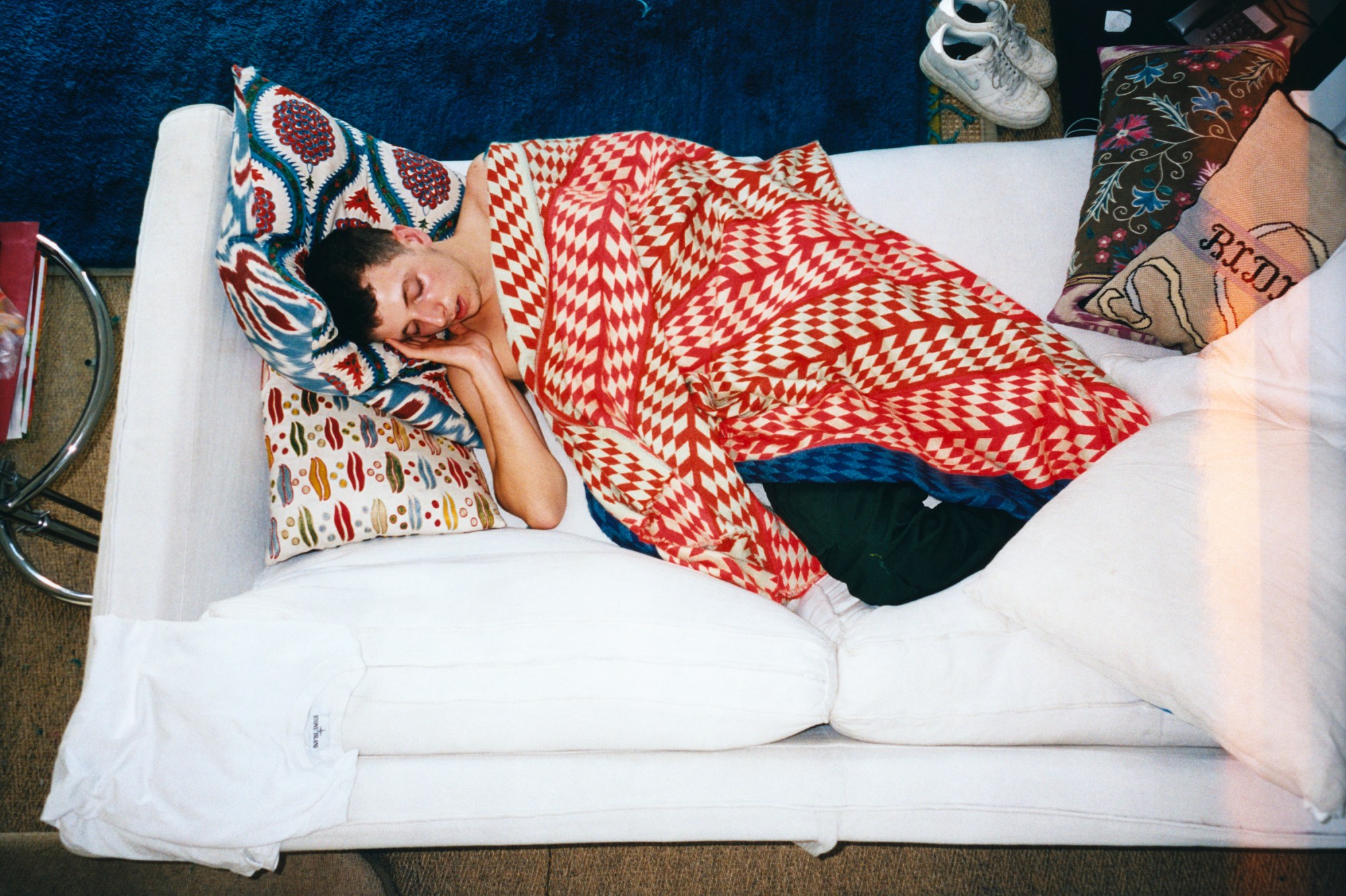 Photo by Evie Shandilya with a boy in a red blanket sleeping on a white sofa in the book 'I Just Want to Party'