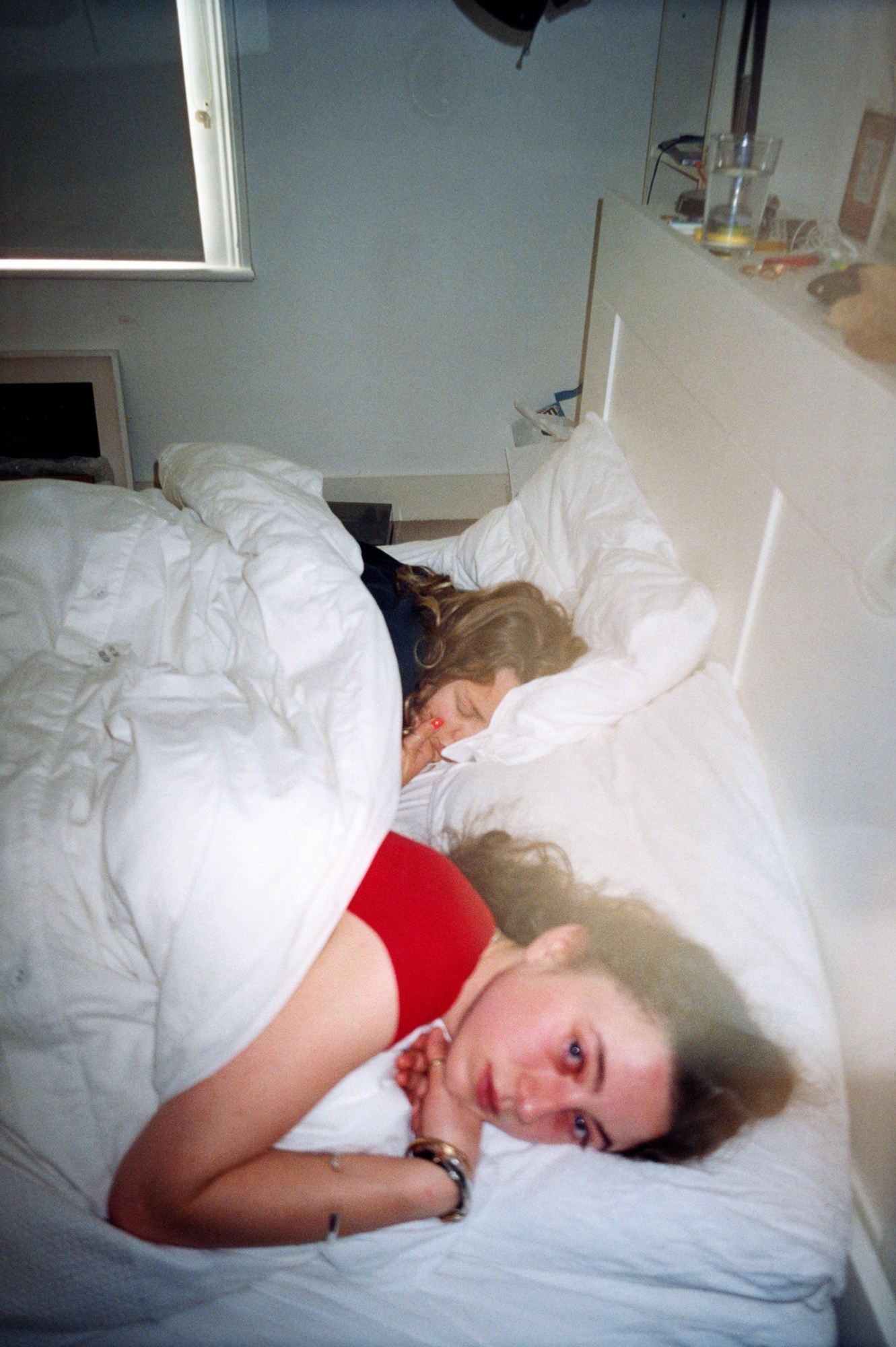 Photo by Evie Shandilya of two friends in bed one sleeping in the book 'I Just Want to Party'