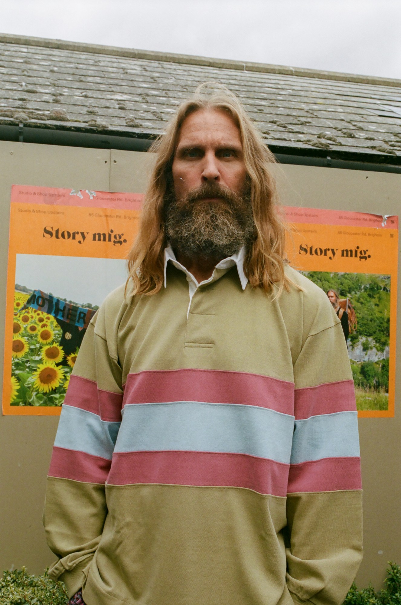 an older man with long blonde hair and a messy beard wears a rugby shirt