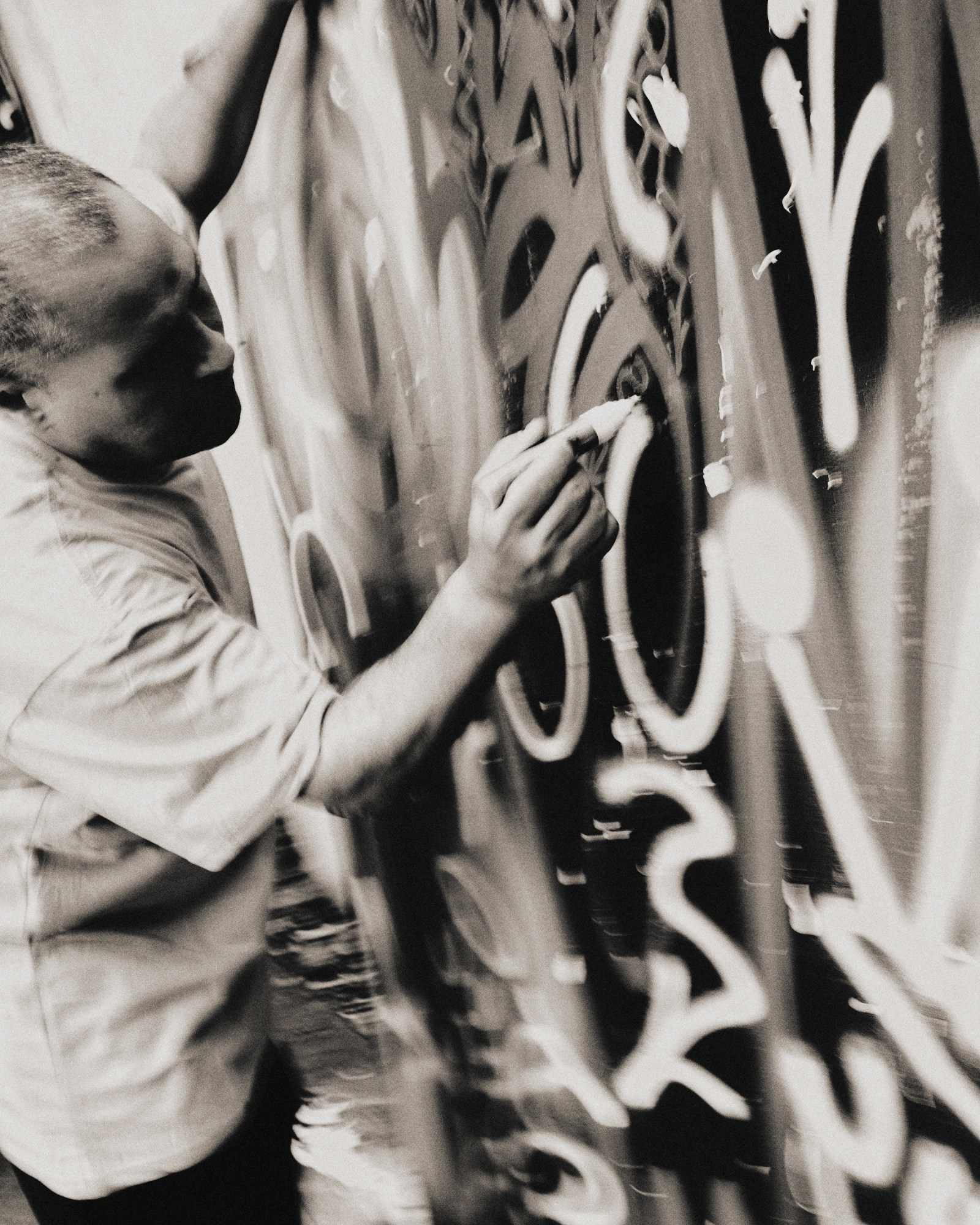 Black-and-white image of Angel Ortiz (LA II) working on a graffiti wall in his NYC Studio