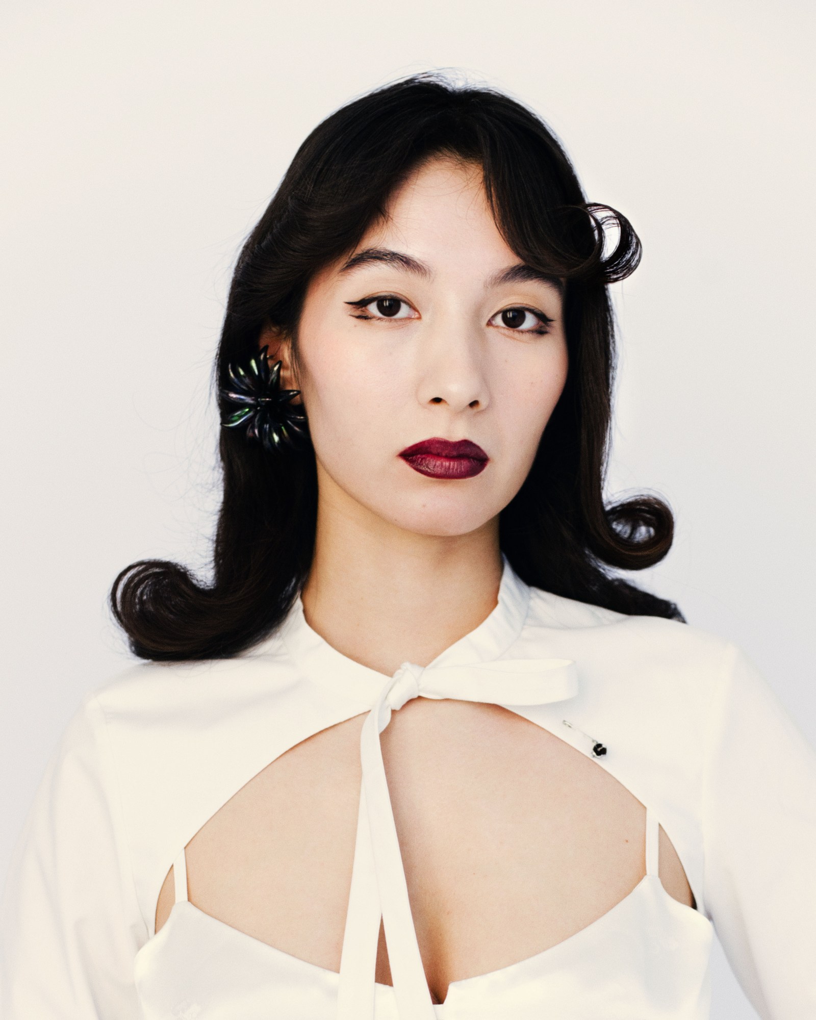 a soviet korean woman with curled hair and dark red lipstick