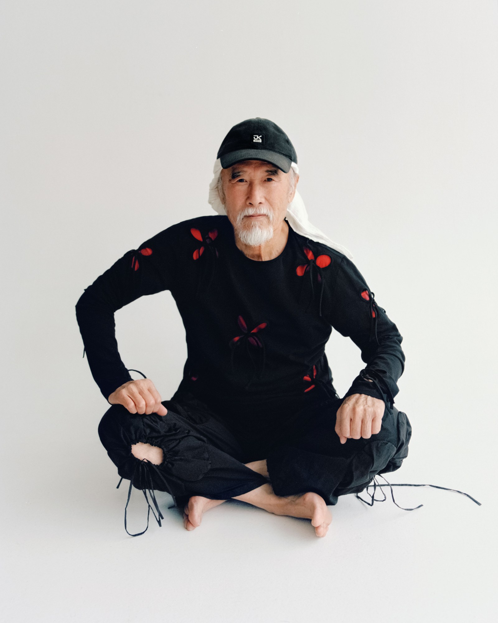 a man with gray hair sitting cross legged on the floor