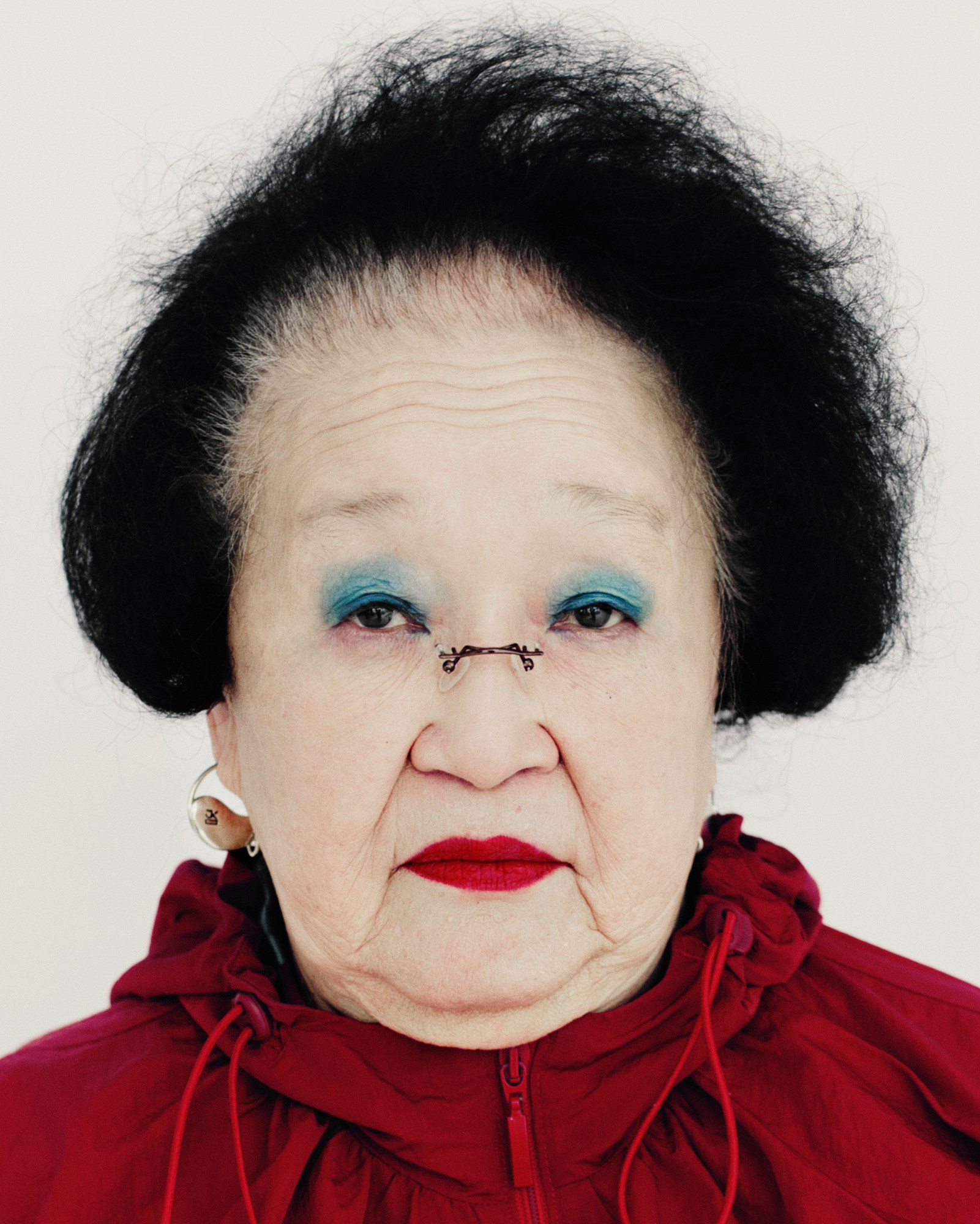 a soviet korean woman with dark black hair, blue eyeshadow red lips and glasses