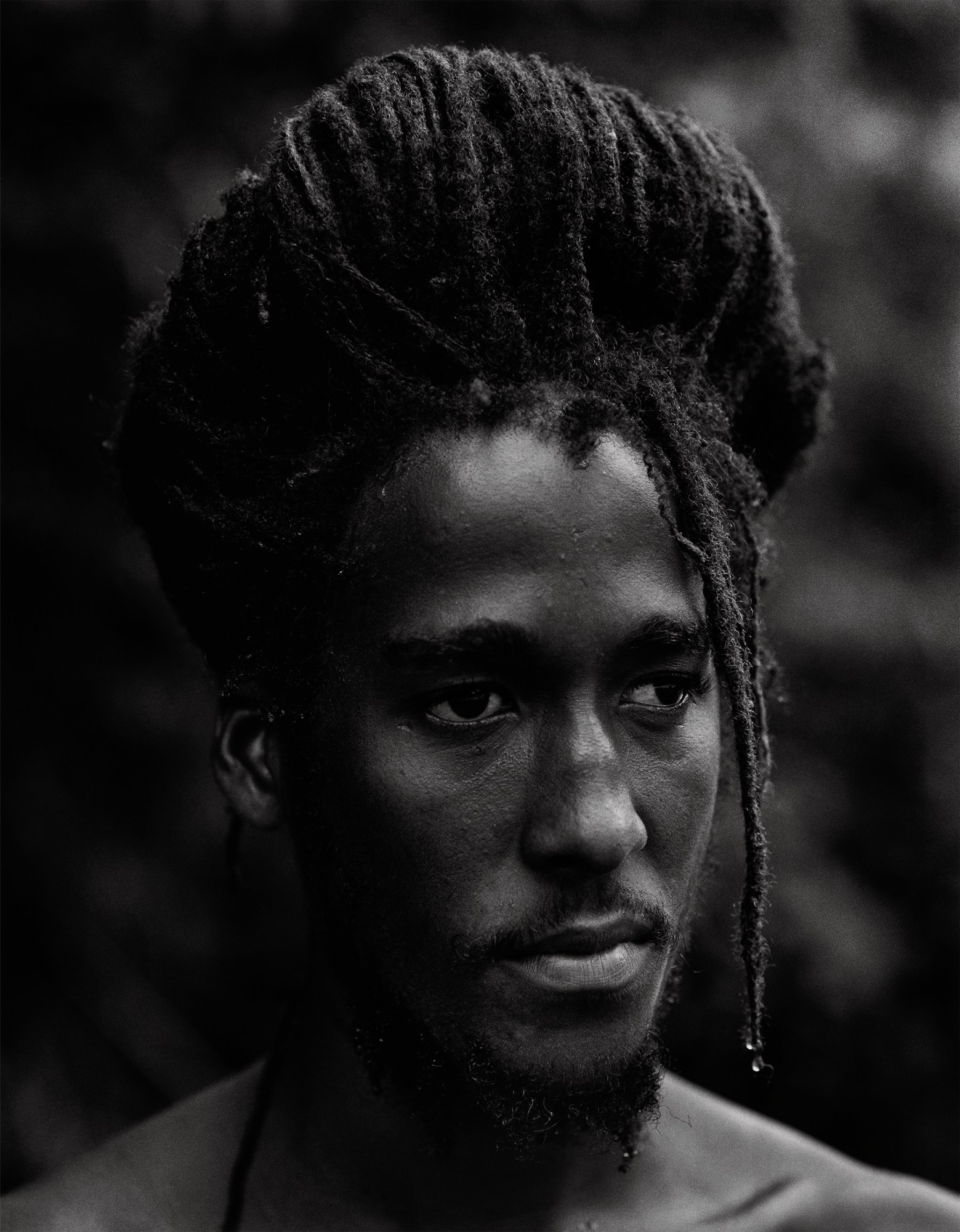 sepia toned close up image of a man with beard and dreads