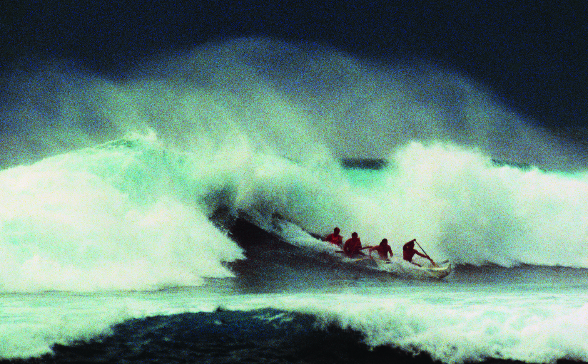 four surfers taking on a wave during a storm