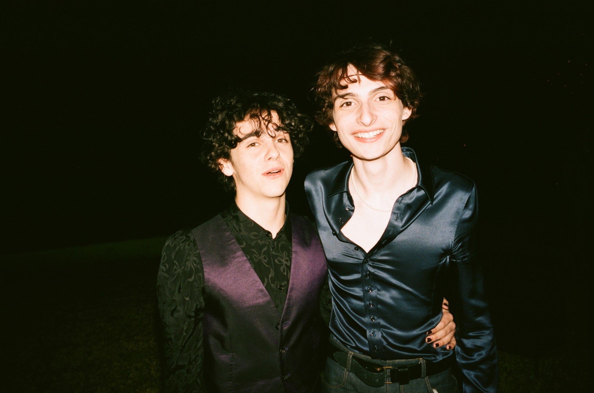 jack dylan glazer and finn wolfhard pose together wearing silky formal shirts