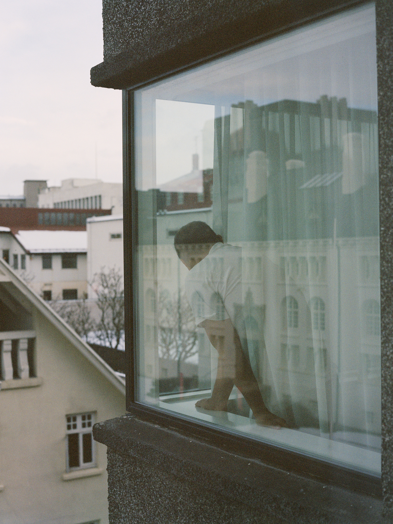 Photograph by Shaniqwa Jarvis of people of a man looking out a window in a city