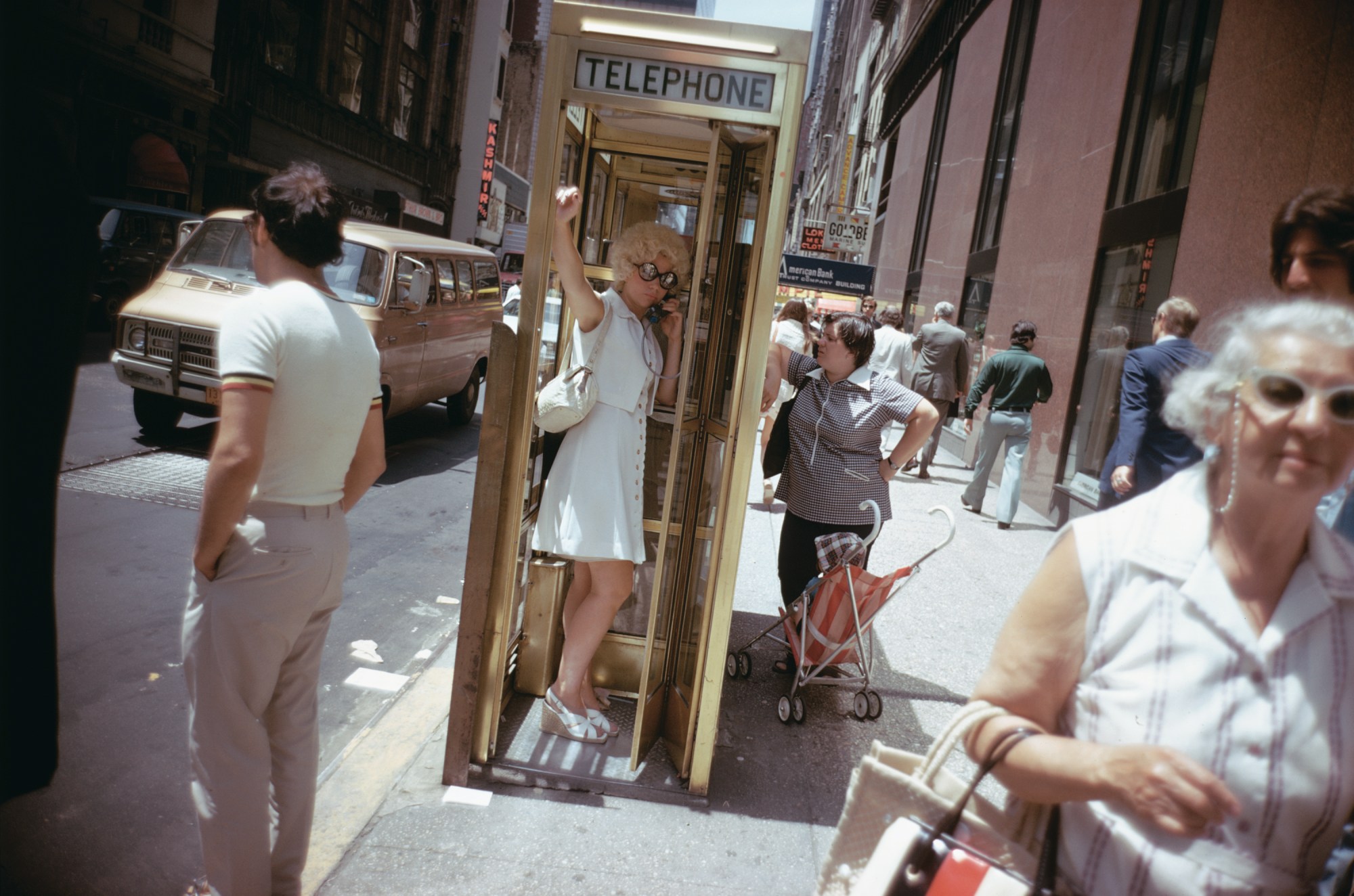 a woman with blonde hair standing in a telephone booth in new york city 70s