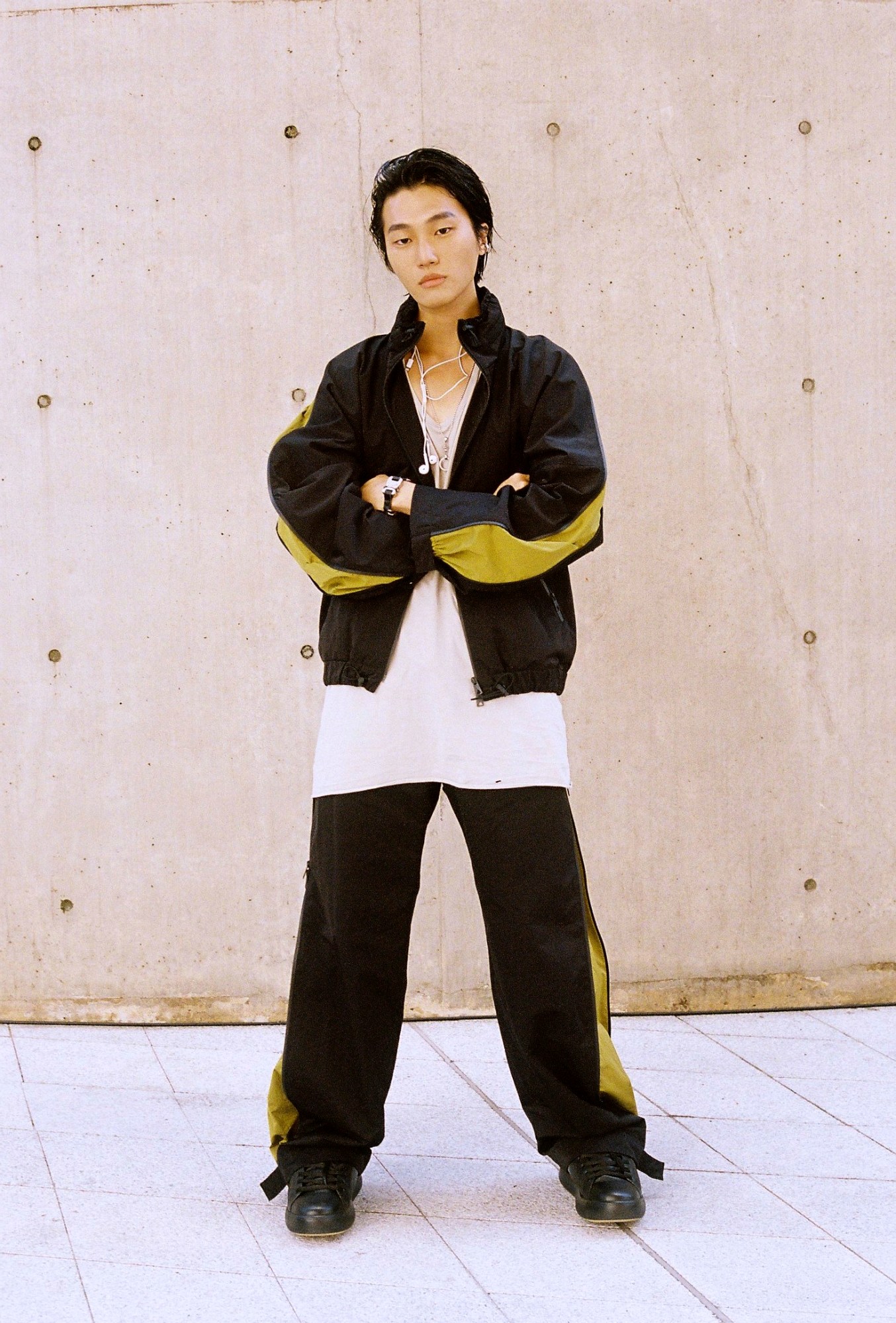 a korean model wears a black and yellow tracksuit with a pair of wired headphones