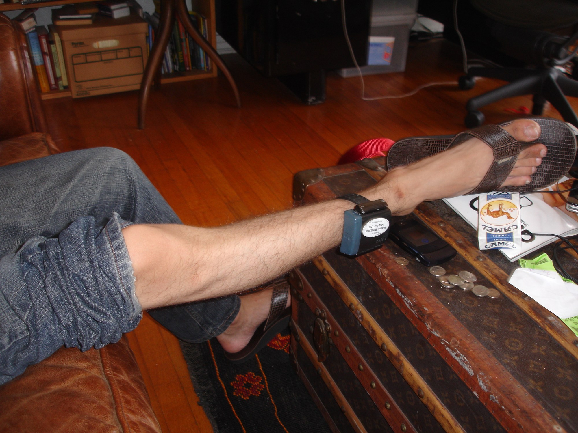 a leg wearing a security tag rests on a busy coffee table