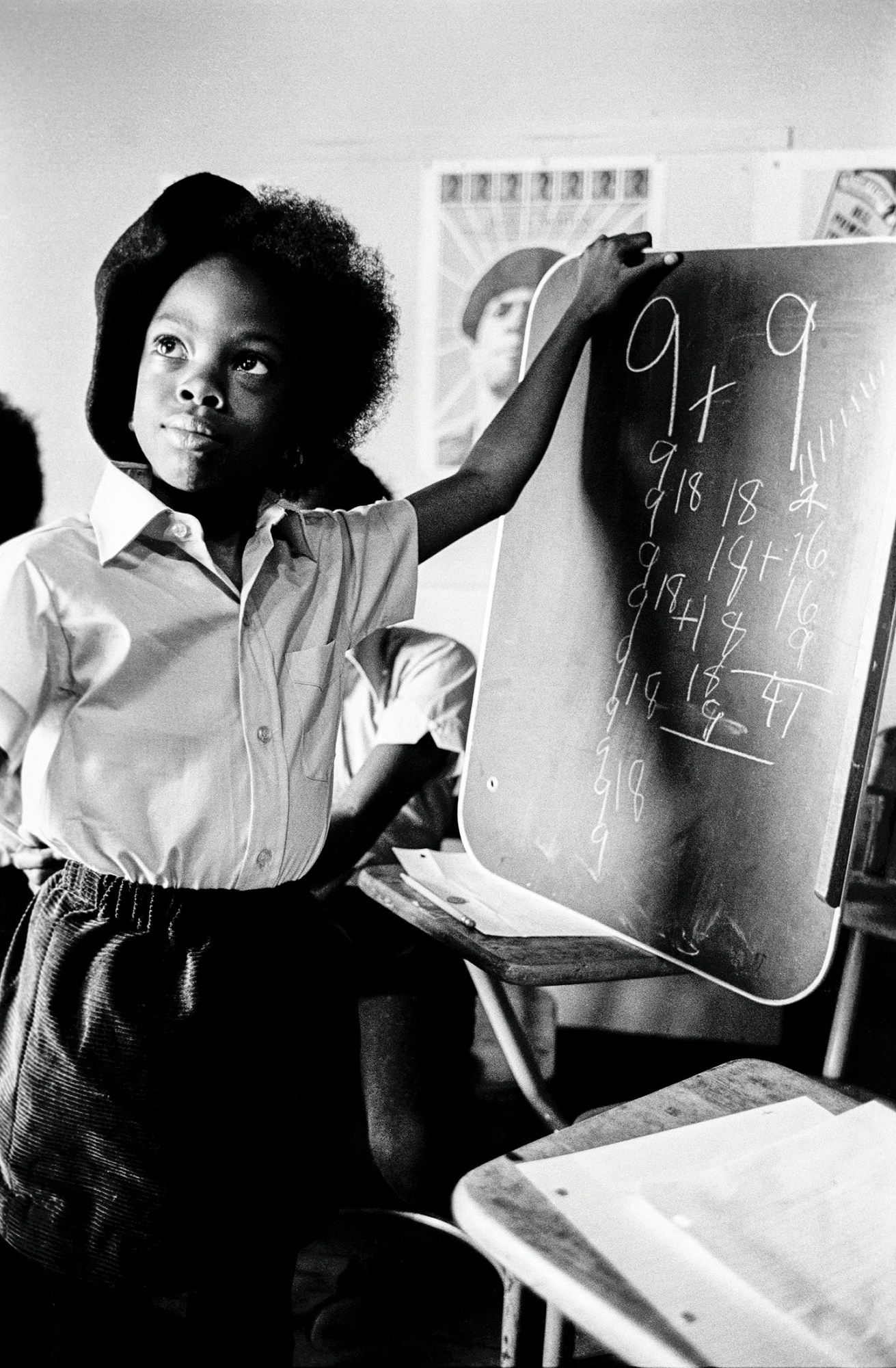 black-and-white photo of a young girl doing maths on a chalk boars