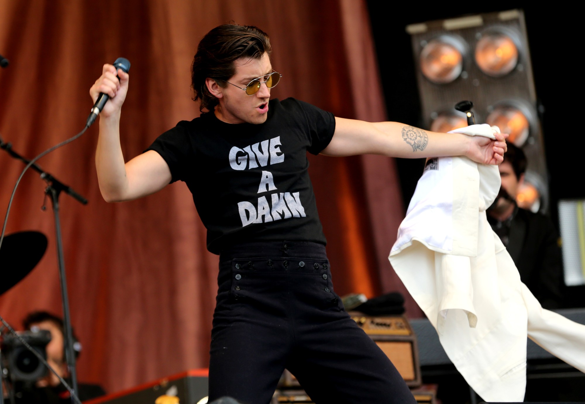 alex on stage in black trousers and a tee that reads GIVE A DAMN