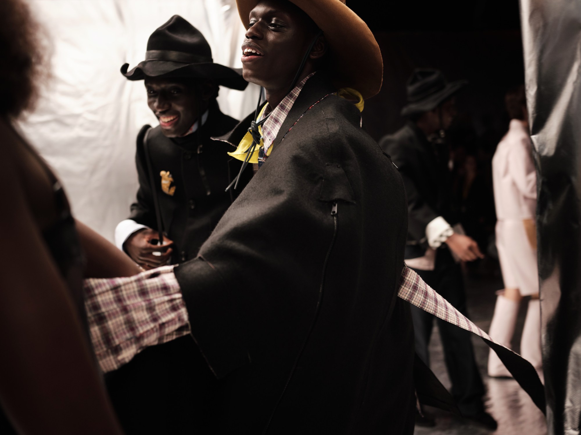 a group of men backstage at a fashion show.