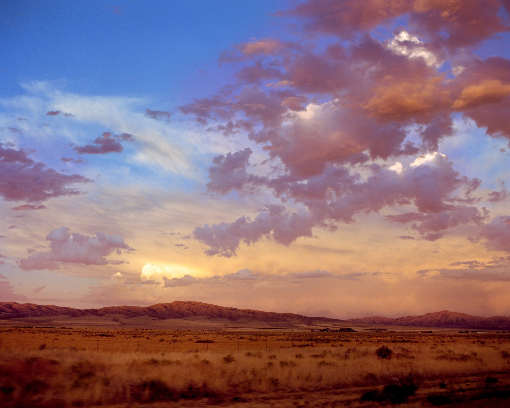 Photograph by Caroline Tompkins of a sunset over a mountainous view and dry grass